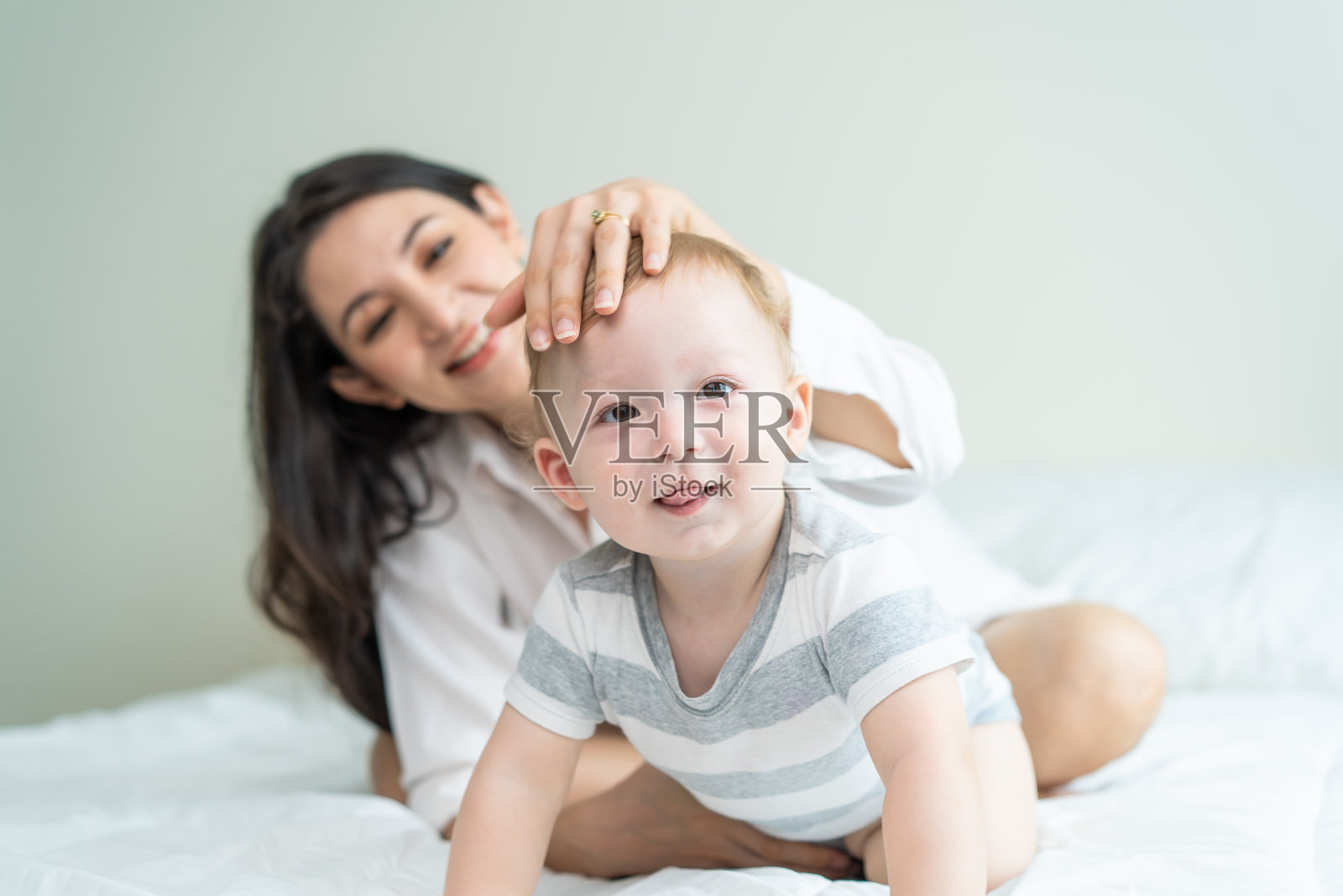 白种人幸福家庭的肖像微笑,看着相机在卧室。年轻漂亮的女父母,妈妈穿着睡衣躺在小男孩的床上享受清晨醒来在家的活动照片摄影图片