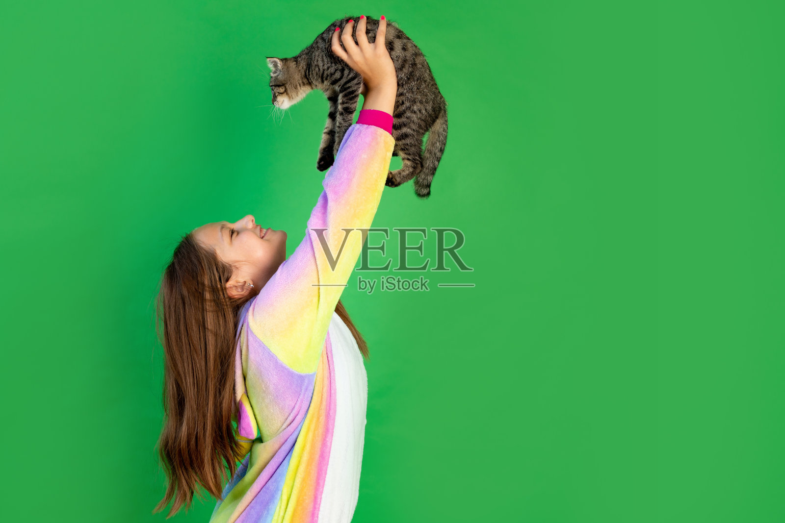 可爱的女孩,手里拿着一只猫。绿色隔离背景。空间的文本。动物作为礼物照片摄影图片