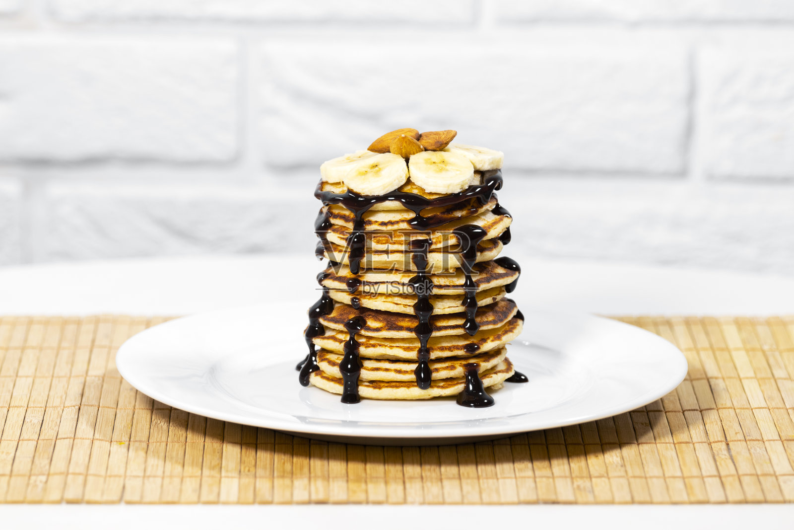 巧克力糖浆煎饼,杏仁坚果和香蕉。一堆薄饼。美味的早餐和健康的食物照片摄影图片