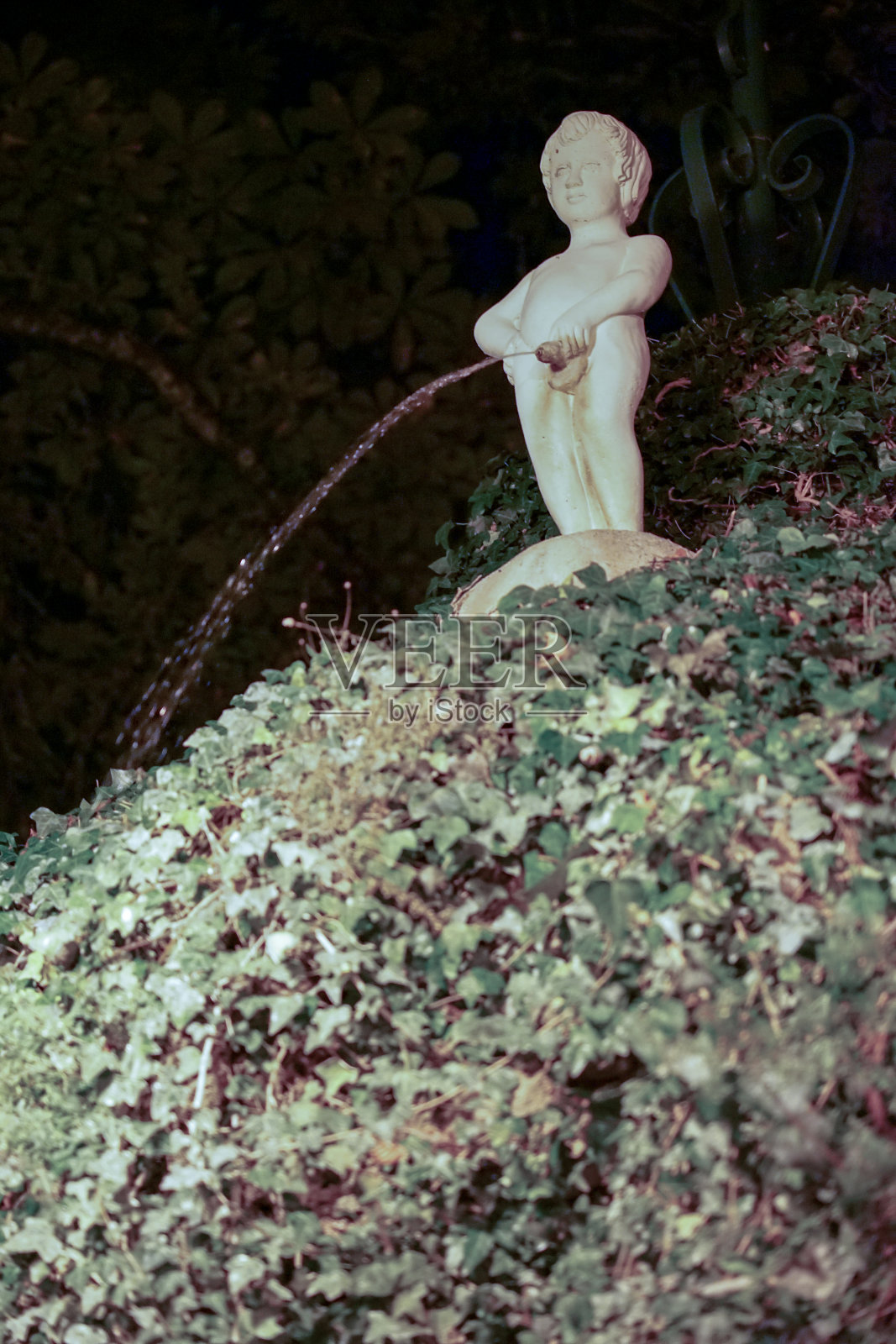 一个孩子的石像在阿连特霍镇的一个花园中小便。照片摄影图片