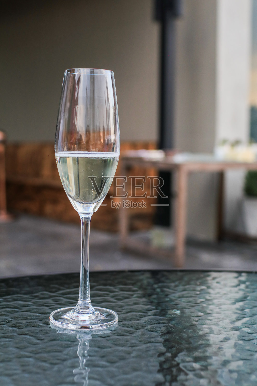 室外咖啡厅桌上的一杯白葡萄酒,特写镜头。在户外兴高采烈地喝着白葡萄酒庆祝,人们在餐馆里吃晚餐。照片摄影图片