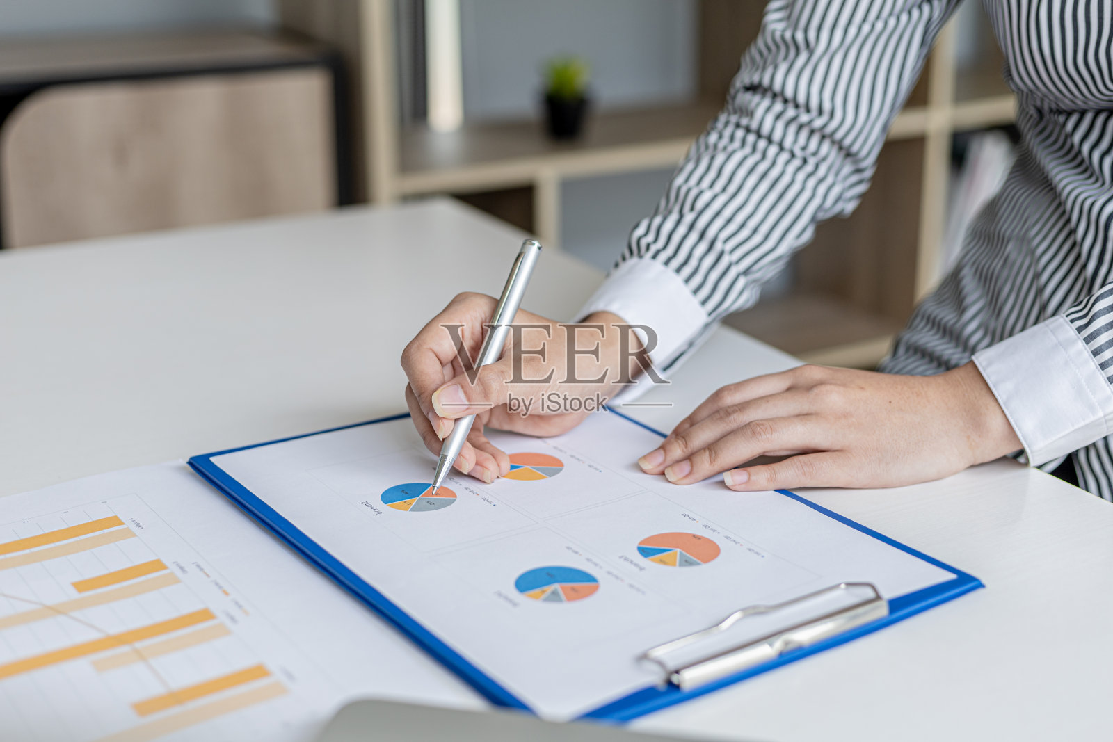 审计员指着财务报表,她检查了财务部门准备的文件中的财务信息,然后在会议上提交给管理层。照片摄影图片