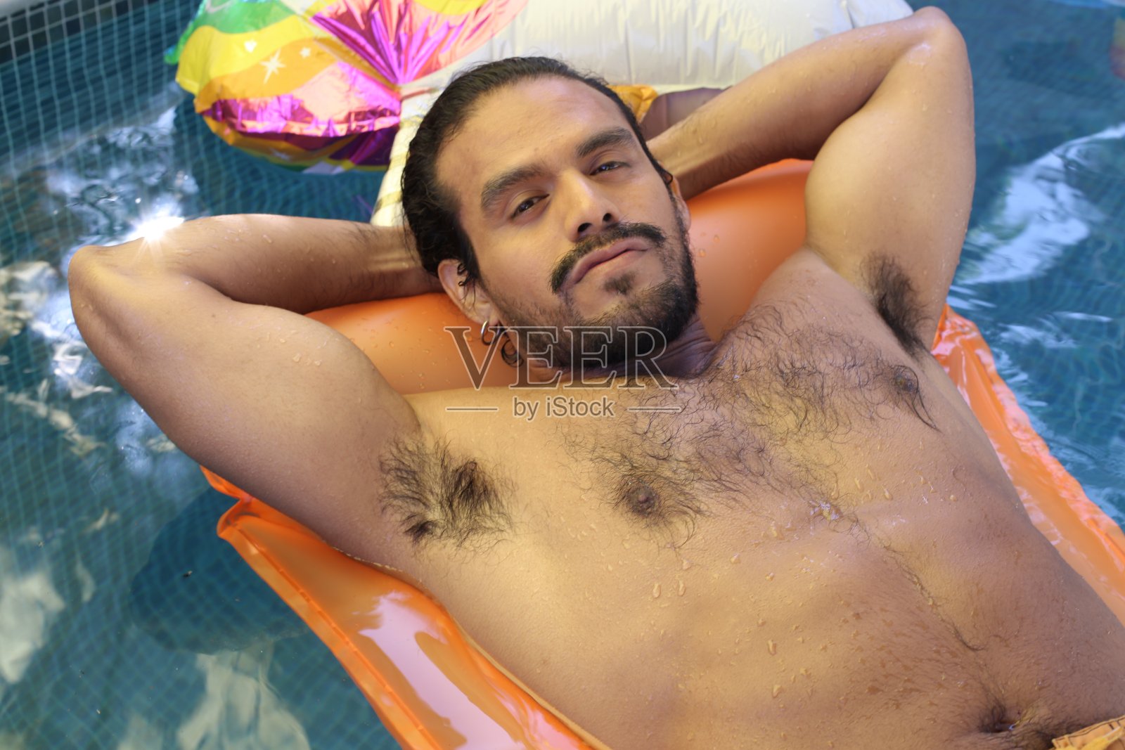 有魅力的少数民族男子漂浮在游泳池里照片摄影图片