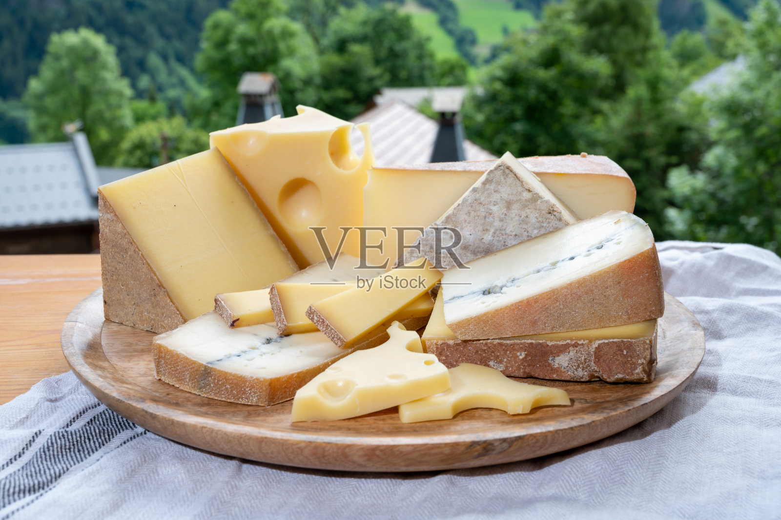 奶酪系列,木板上有法国奶酪comte, beaufort, abondance, emmental, morbier和上萨瓦的法国山村照片摄影图片
