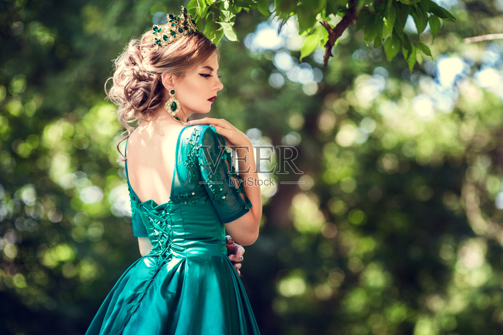 一名身穿绿色连衣裙的年轻女子在一片神奇的森林里探险照片摄影图片