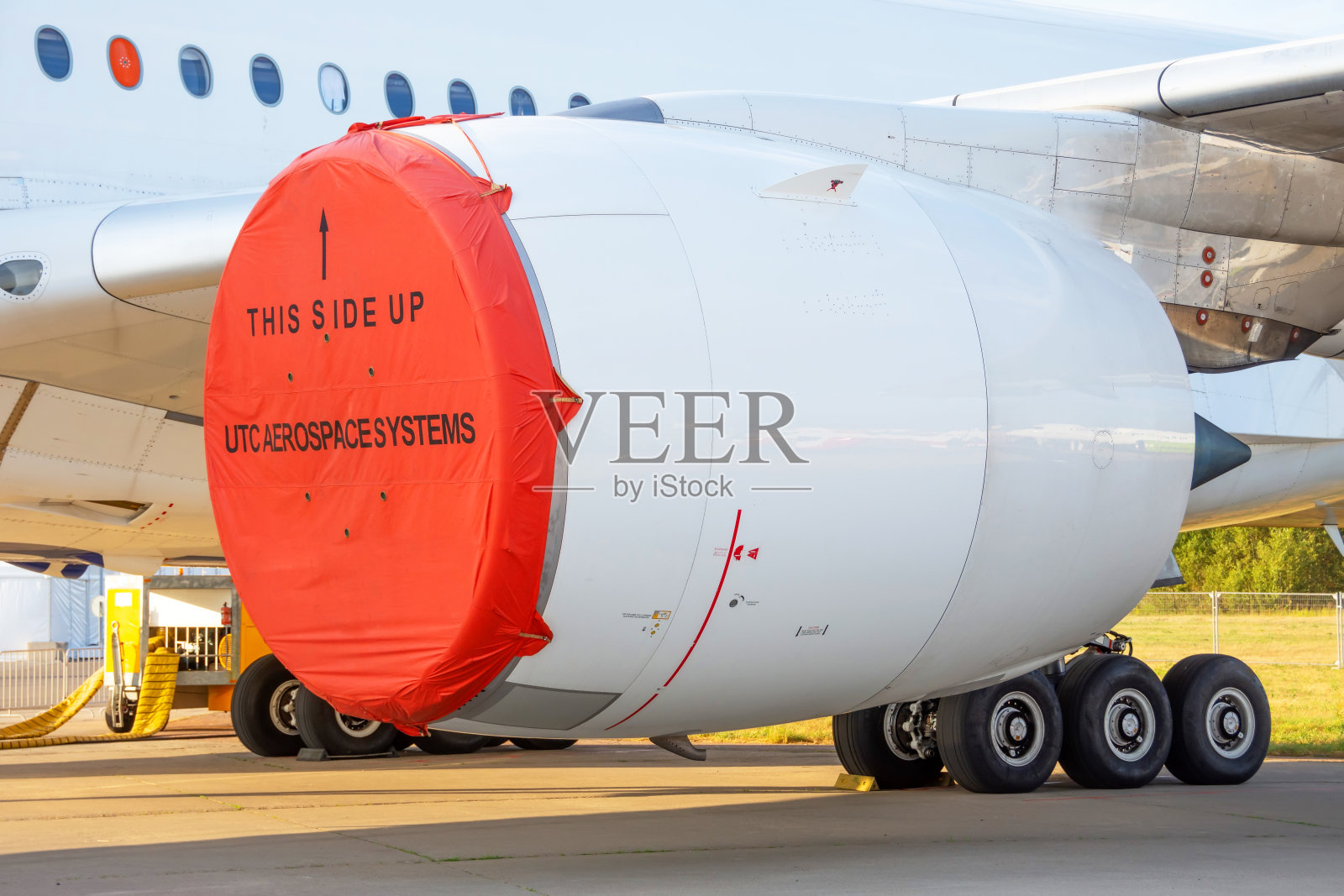 在停车场测试机翼下有红色发动机罩的飞机。照片摄影图片