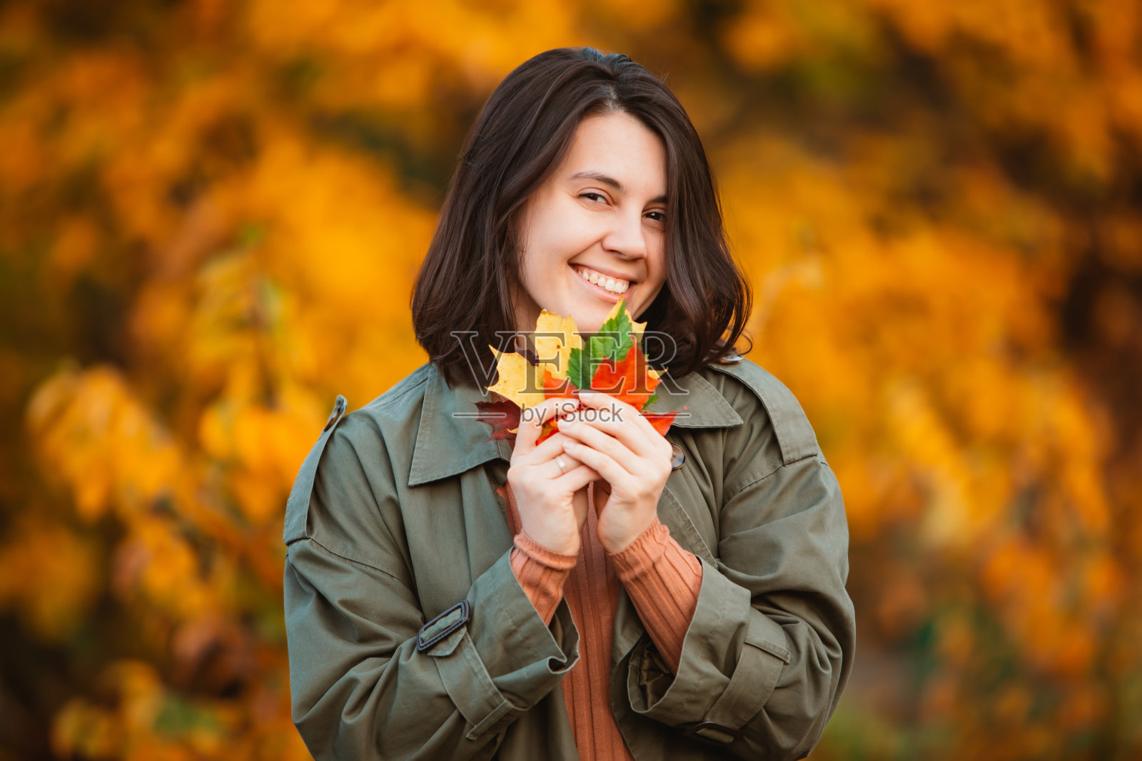 微笑的女人在金色的秋叶前照片摄影图片