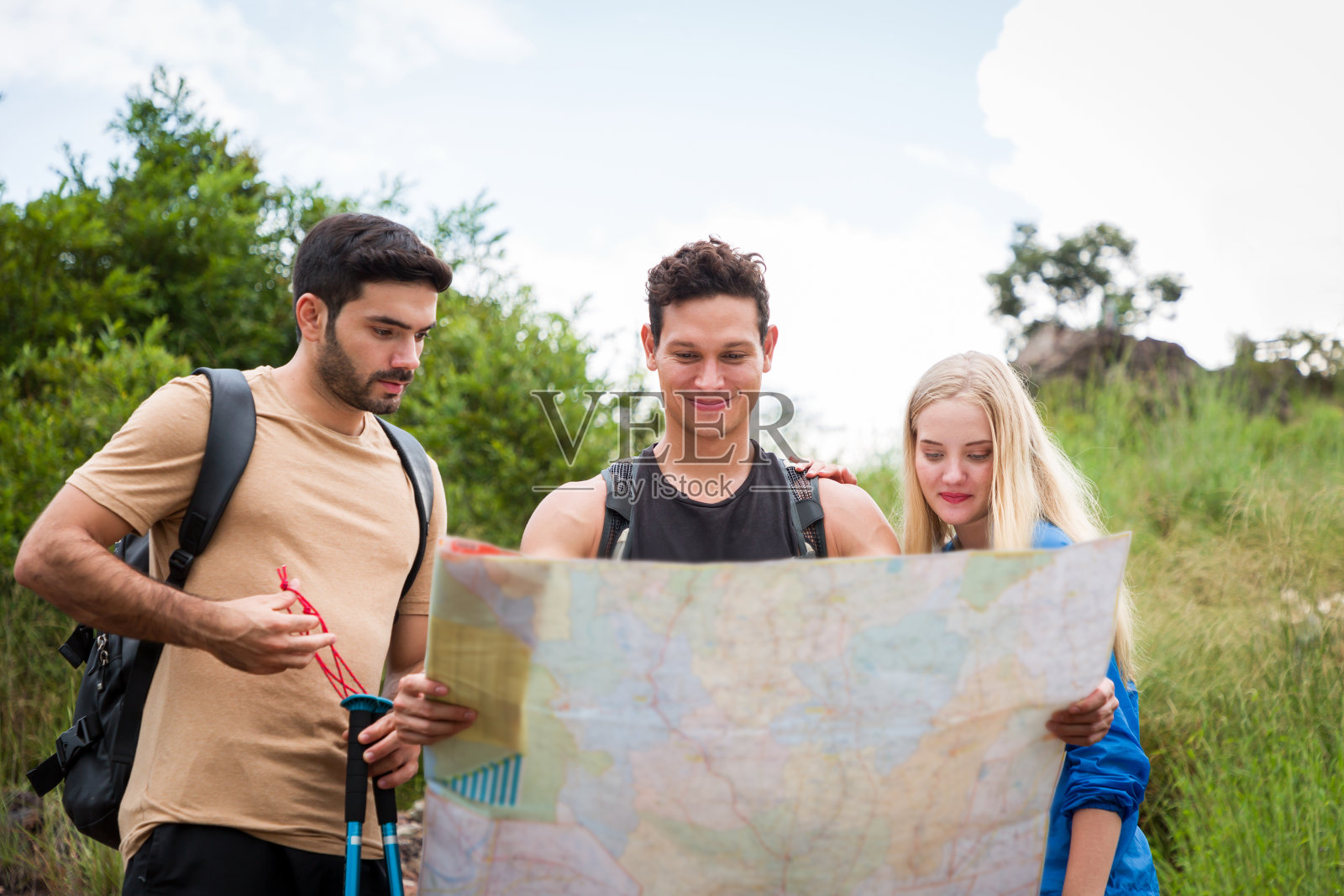 一群年轻的背包客在山上背着背包看地图。一群背包旅行者走在山林小径上照片摄影图片