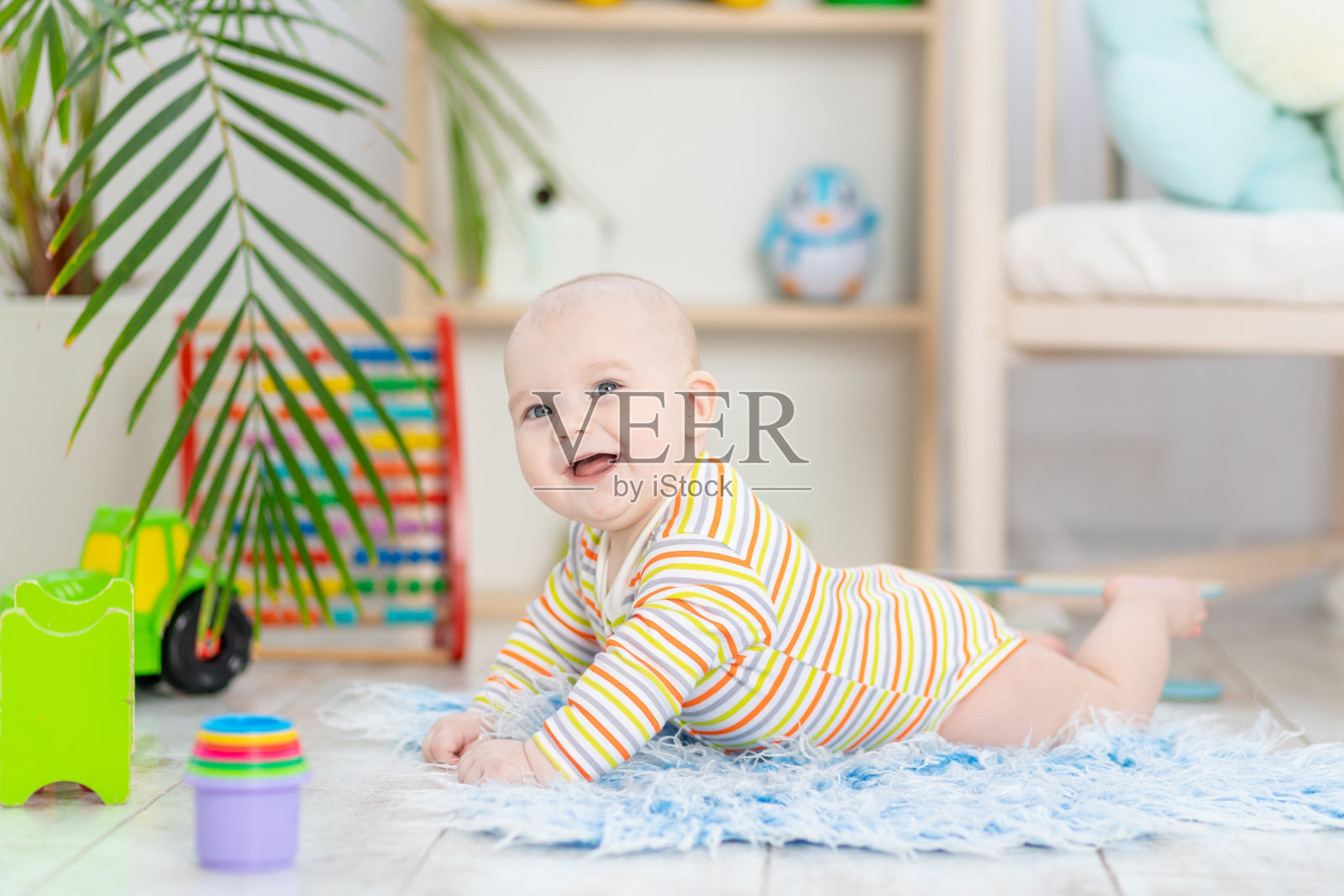童男宝宝在儿童房的玩具间,可爱有趣微笑的小宝贝在地板上玩耍,儿童发展的概念和游戏照片摄影图片