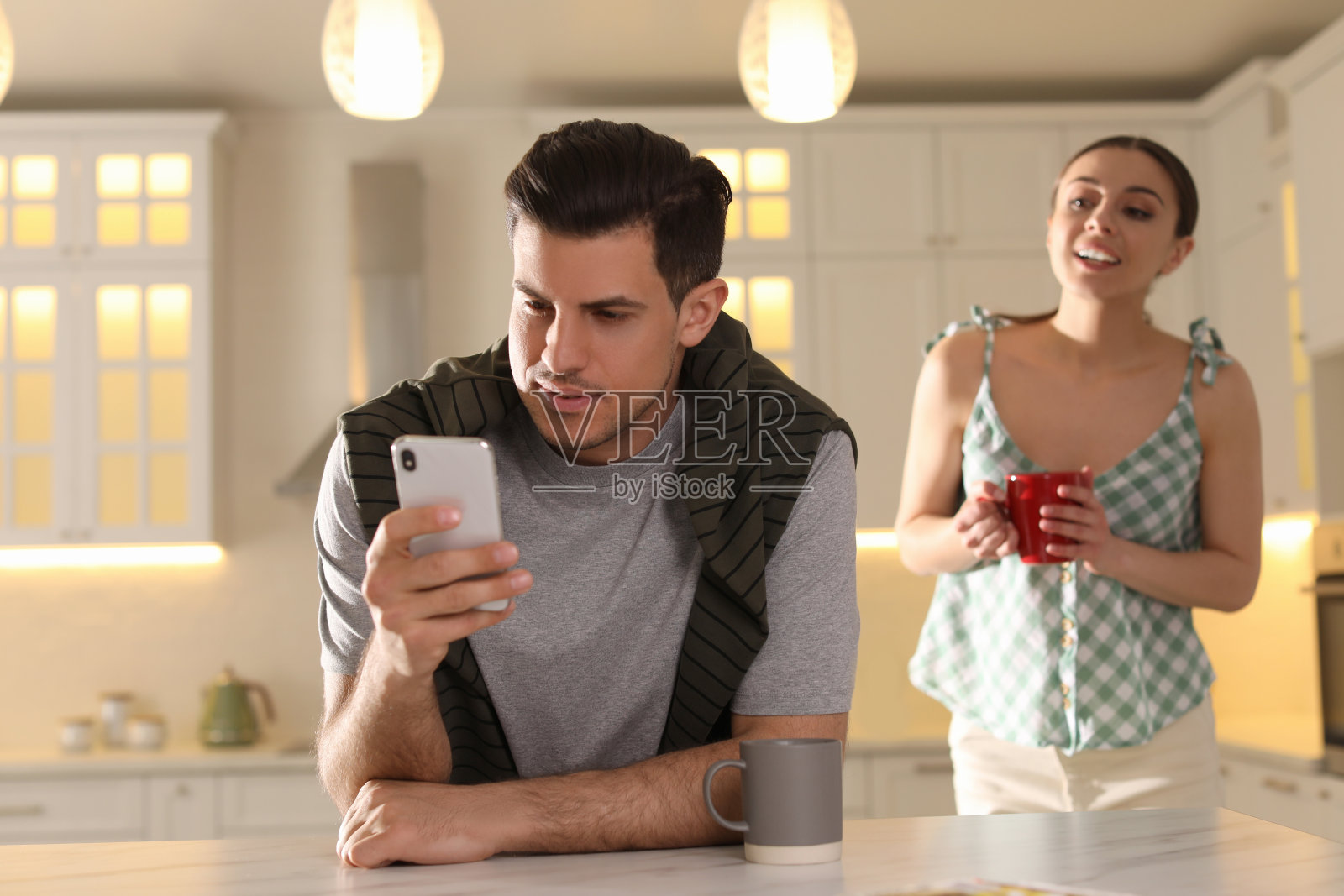 多疑的女人在家里偷看男友的智能手机。嫉妒的关系照片摄影图片