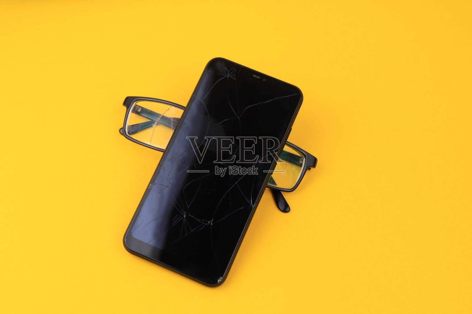 打碎的眼镜和智能手机。有选择性的重点。照片摄影图片