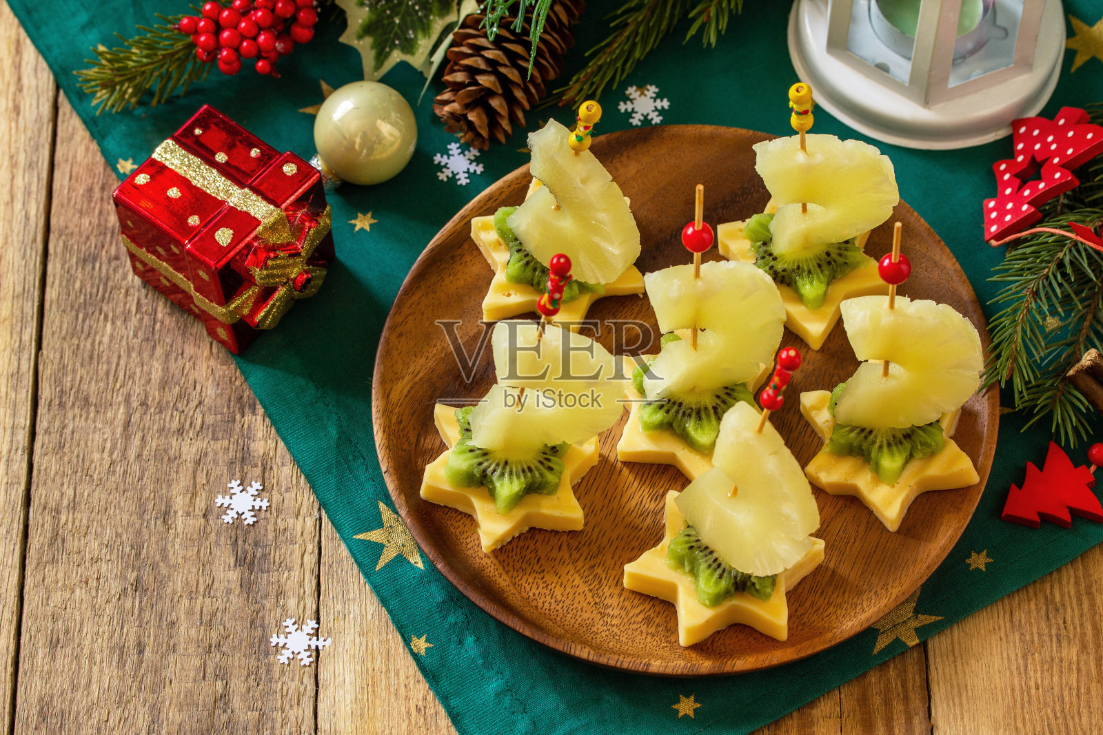 圣诞桌上的节日小吃。水果点心配奶酪,猕猴桃和菠萝。副本的空间。照片摄影图片
