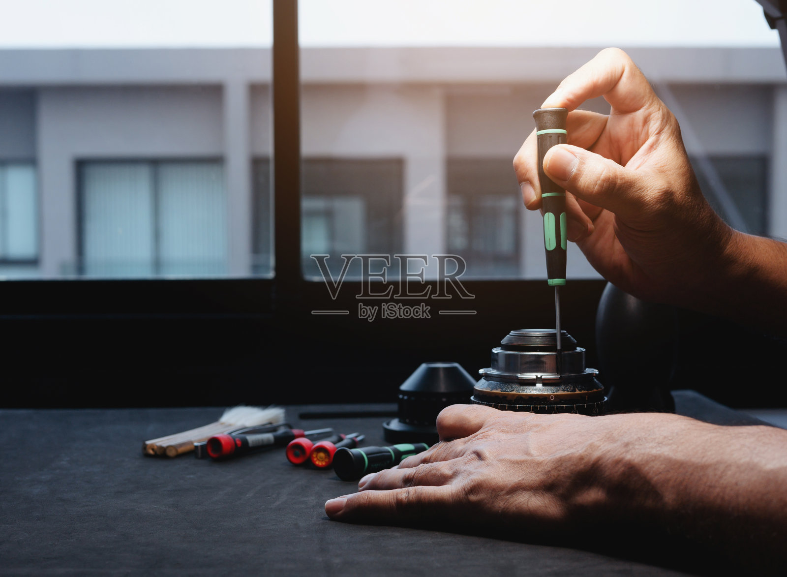 使用螺丝刀拆卸电影镜头的固定螺丝进行维修。照片摄影图片