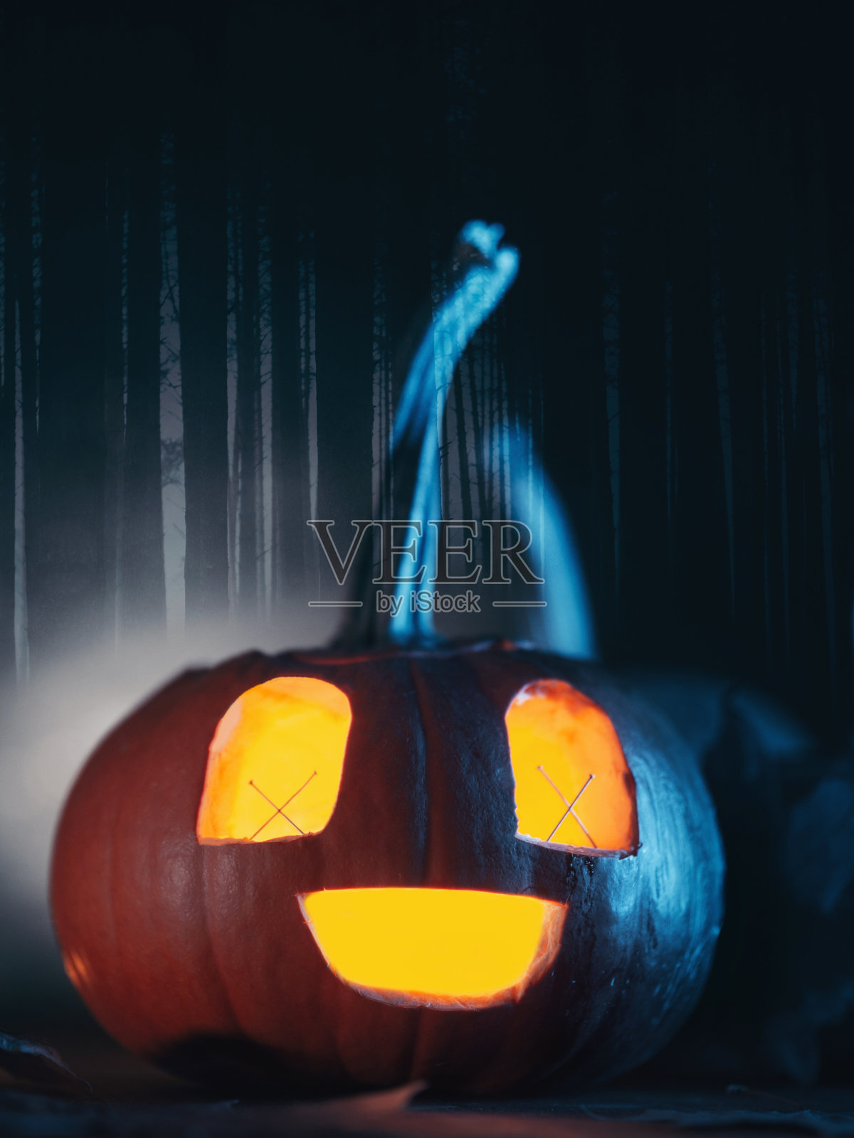 发光的南瓜灯特写,阴暗的森林背景照片摄影图片