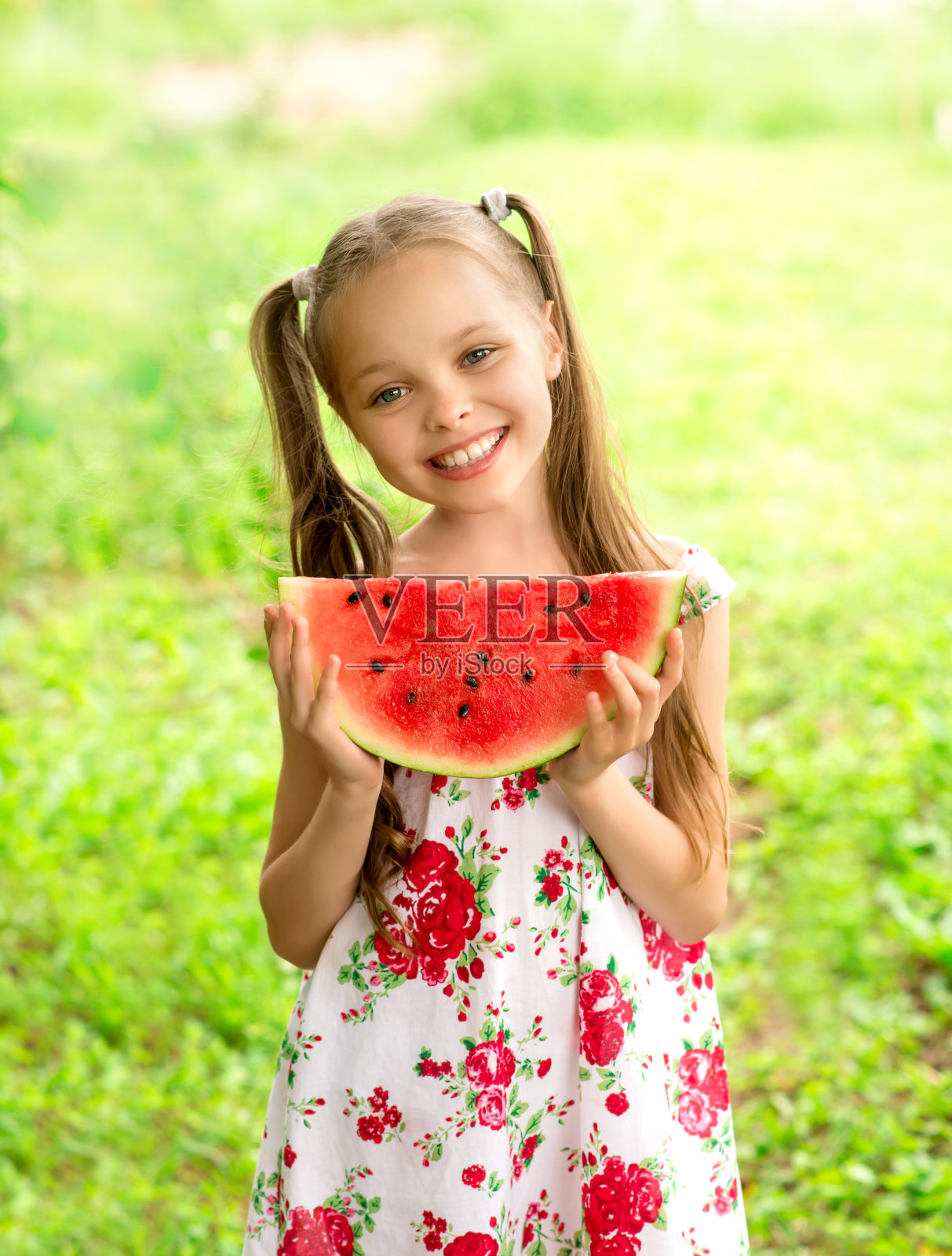 蓝眼睛的小女孩微笑着吃着一片西瓜照片摄影图片