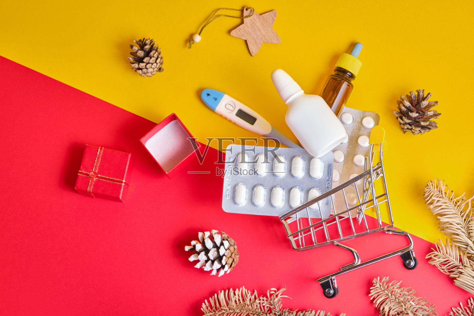 在圣诞和新年,感冒和流感季节之前购买药品的黄色红色背景的购物车照片摄影图片