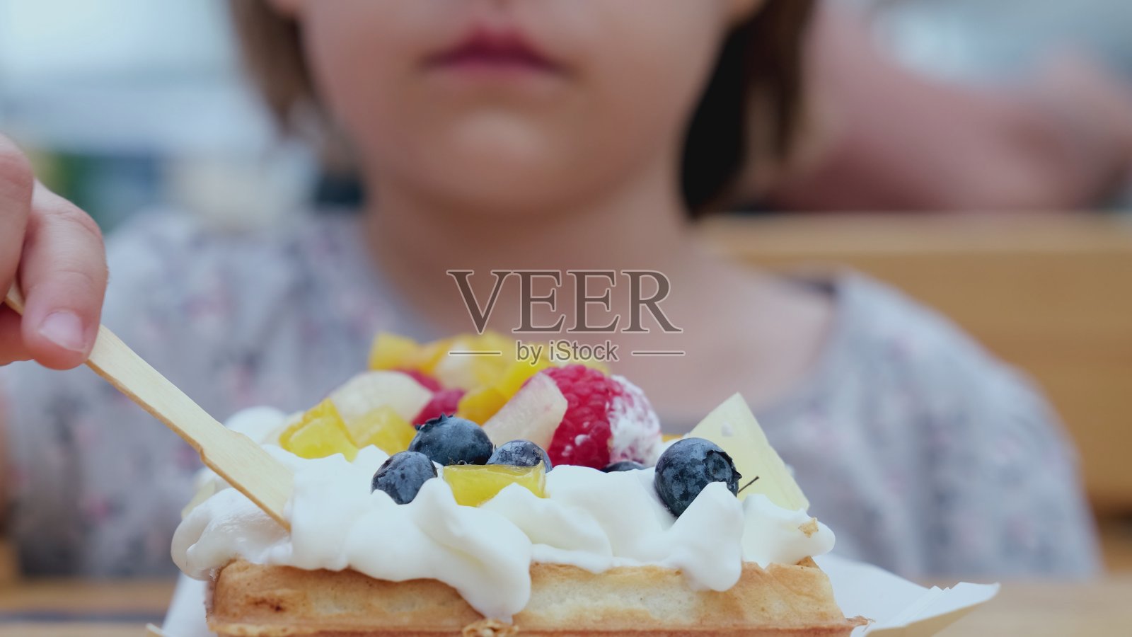 年轻的白种人女孩吃着巨大的美味甜点华夫饼与鲜奶油和新鲜水果照片摄影图片