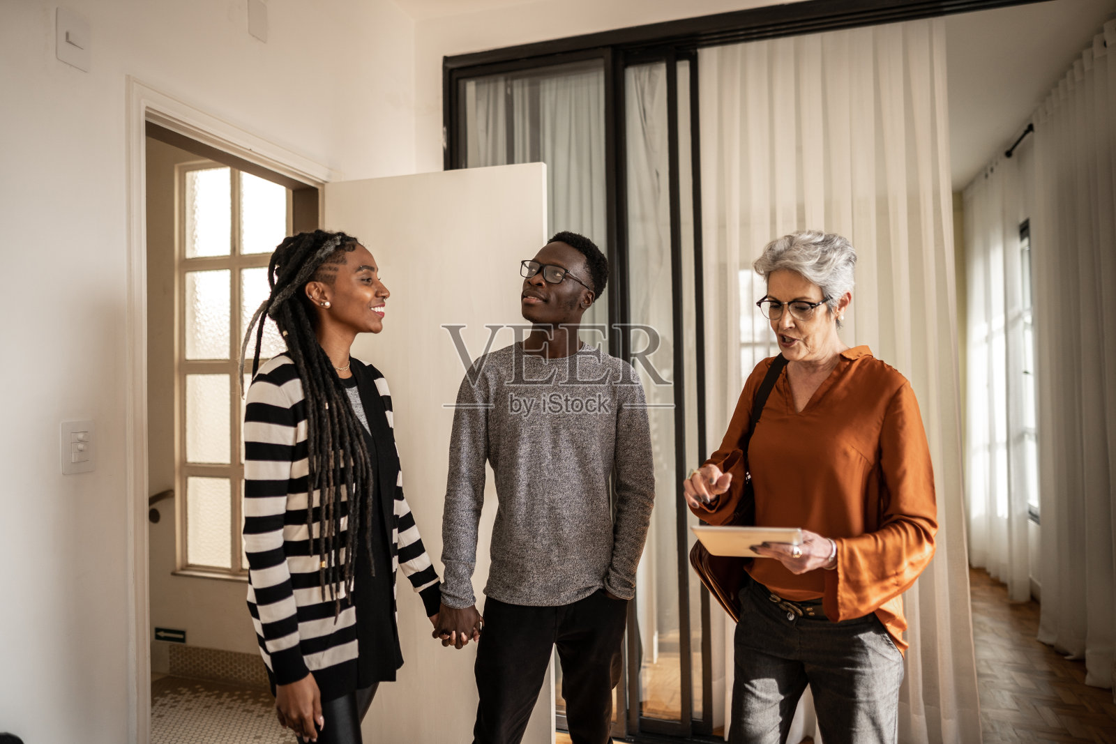 房地产经纪人给年轻夫妇看房子照片摄影图片