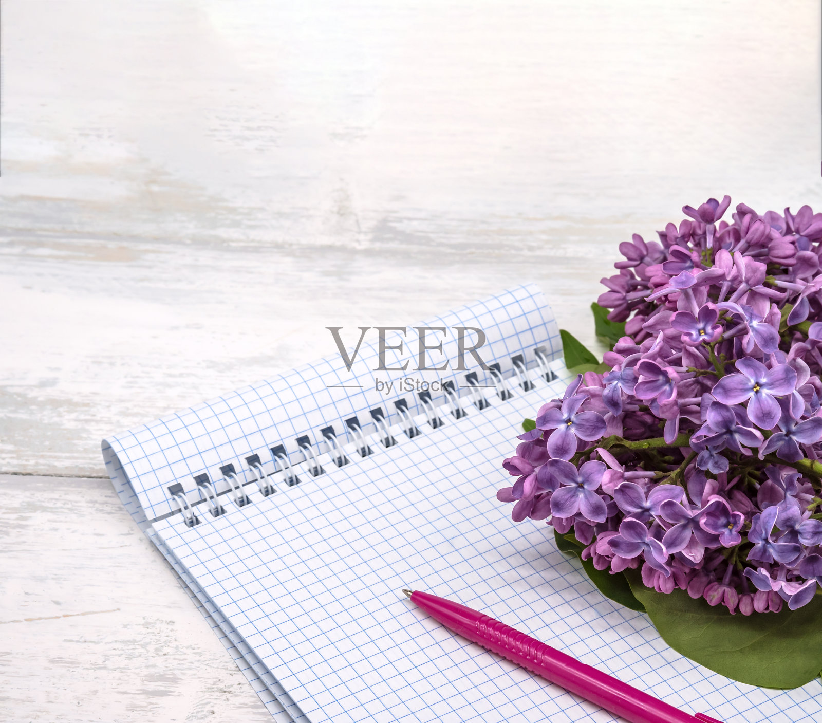 一本笔记本,一支笔和一束花。一个笔记本和一朵花。螺旋笔记本和笔。木制背景上的抄写本。照片摄影图片