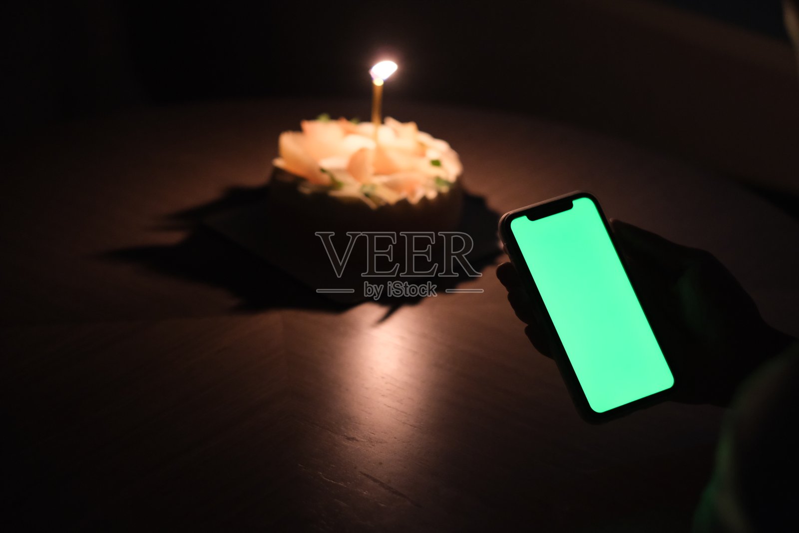 在漆黑的夜晚,手握绿屏手机参加生日聚会照片摄影图片