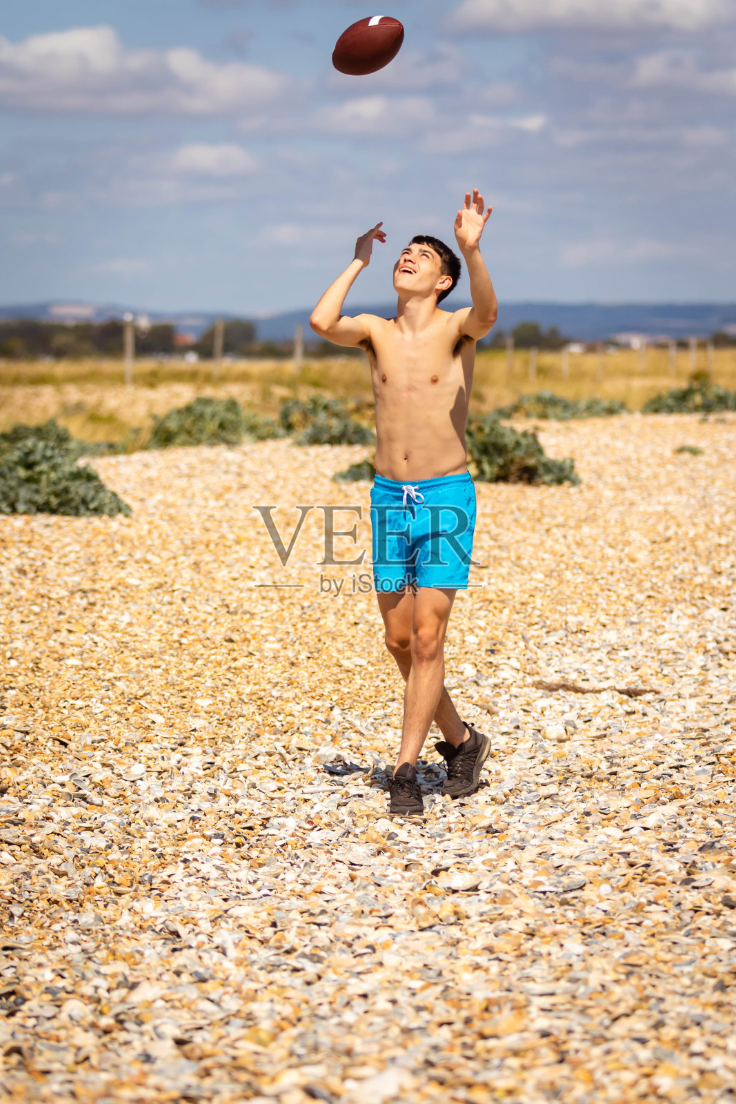 拿着橄榄球在沙滩上奔跑照片摄影图片