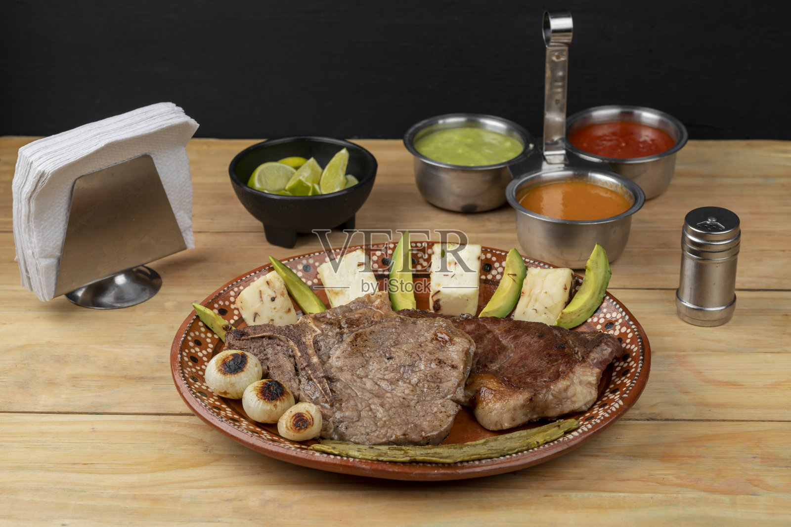 墨西哥菜,切好的肉放在盘子里,木桌上放着牛油果和洋葱照片摄影图片