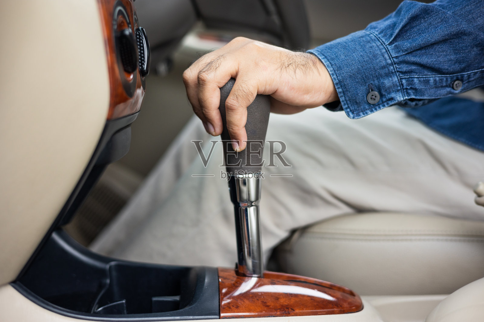 一个年轻人买了一辆新车,他在豪车里用手控制变速杆。公手换档驱动车。照片摄影图片