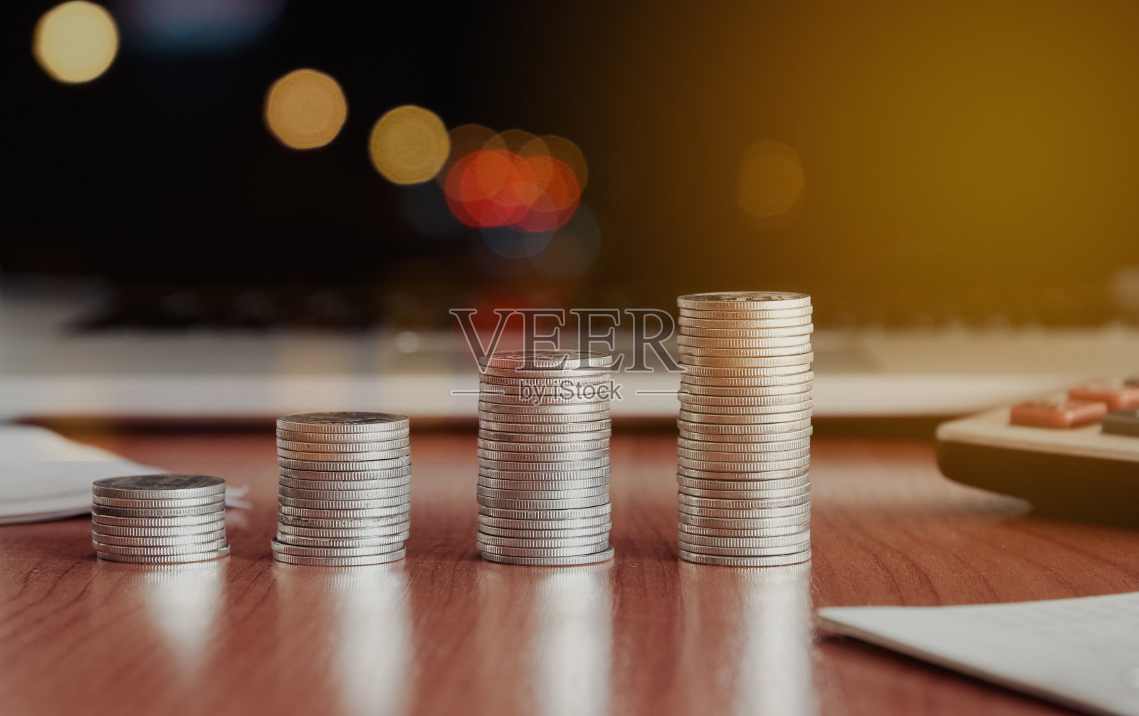 叠钱硬币与笔记本电脑在背景,商业和金融的概念。照片摄影图片