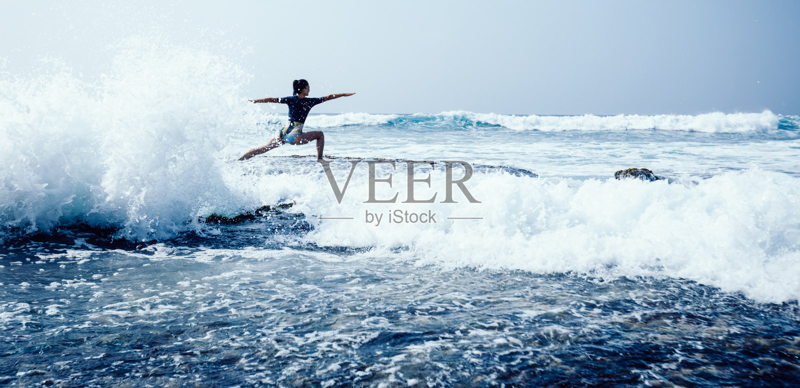 女人在海边悬崖边练习瑜伽,面对汹涌的海浪照片摄影图片