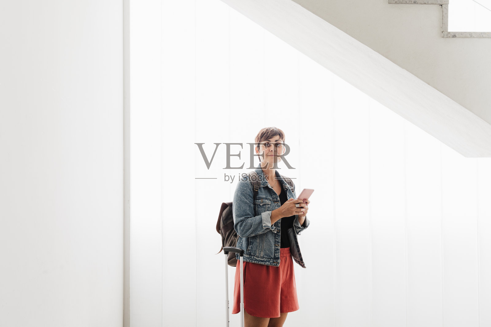 一名白人背包女在火车站候车时使用手机应用。旅游的概念照片摄影图片