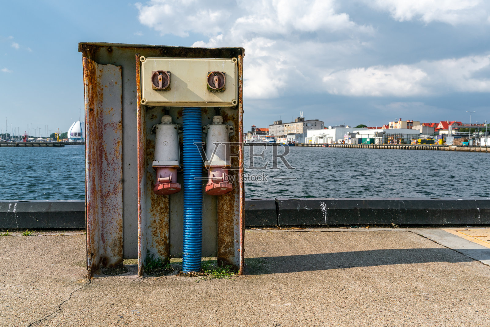 混凝土码头上巨大的旧户外插座的细节,背景是波兰的赫尔港。用于海军舰艇的电力。粗糙的港口技术。照片摄影图片