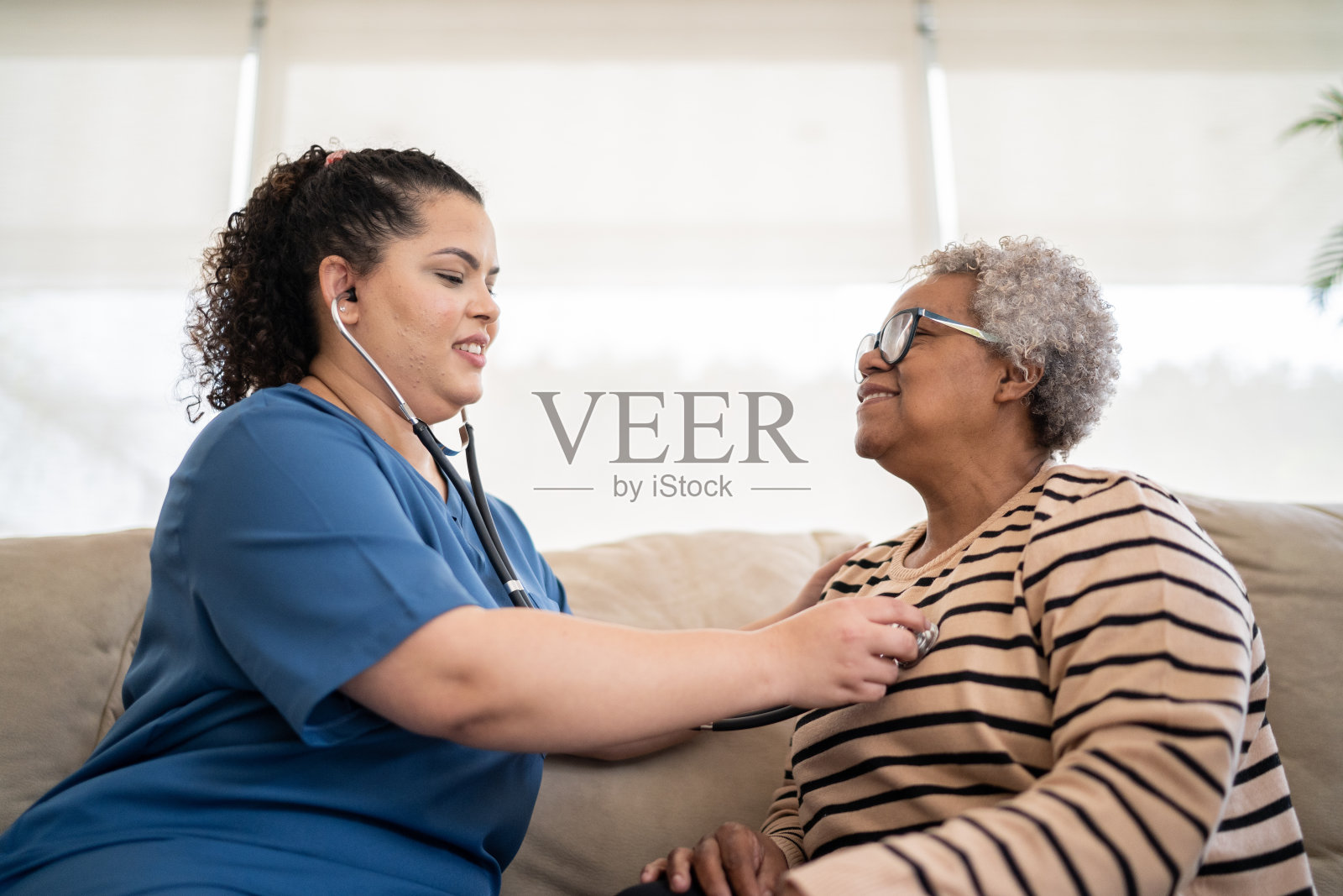 家访时,护士倾听老年病人的心跳照片摄影图片