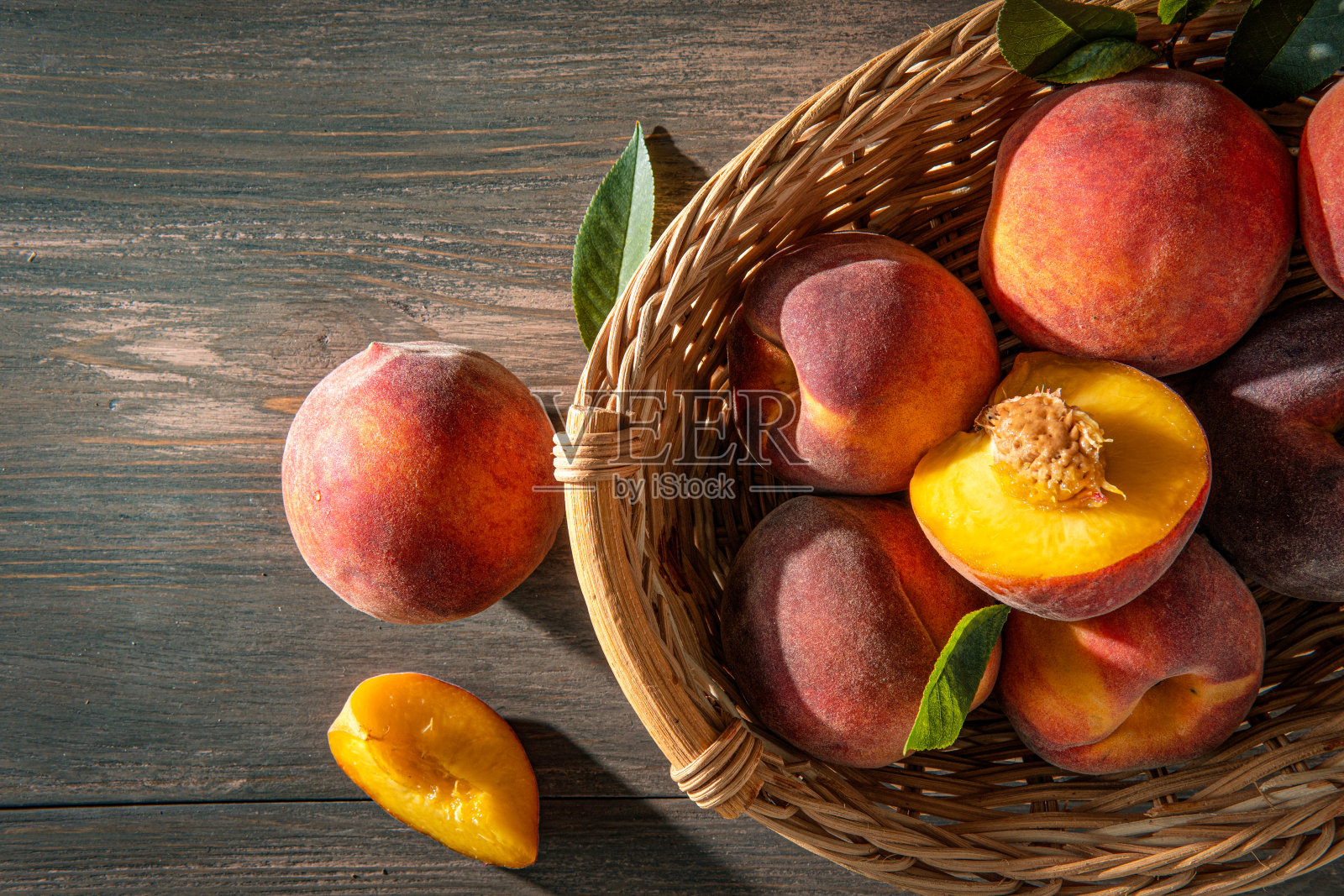 甜熟多汁的桃子,绿色的叶子,木制的背景照片摄影图片