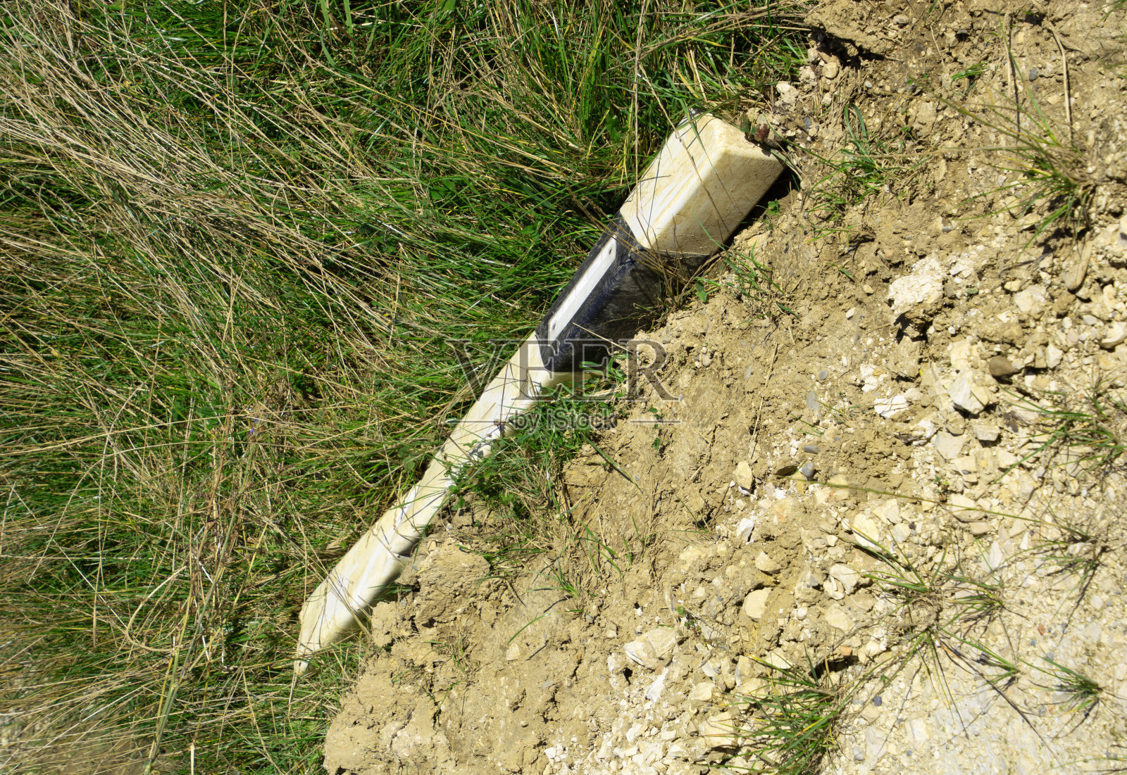 在德国发生车祸后,被撞倒的邮筒躺在路边的泥土中照片摄影图片