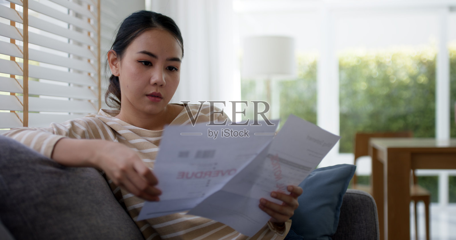 沮丧疲惫的年轻的亚洲悲伤的女人们坐在家里沙发沙发上思考担心税收费用储蓄问题逾期贷款逾期付款covid影响损失的生命感到悲伤忧郁的斗争。照片摄影图片