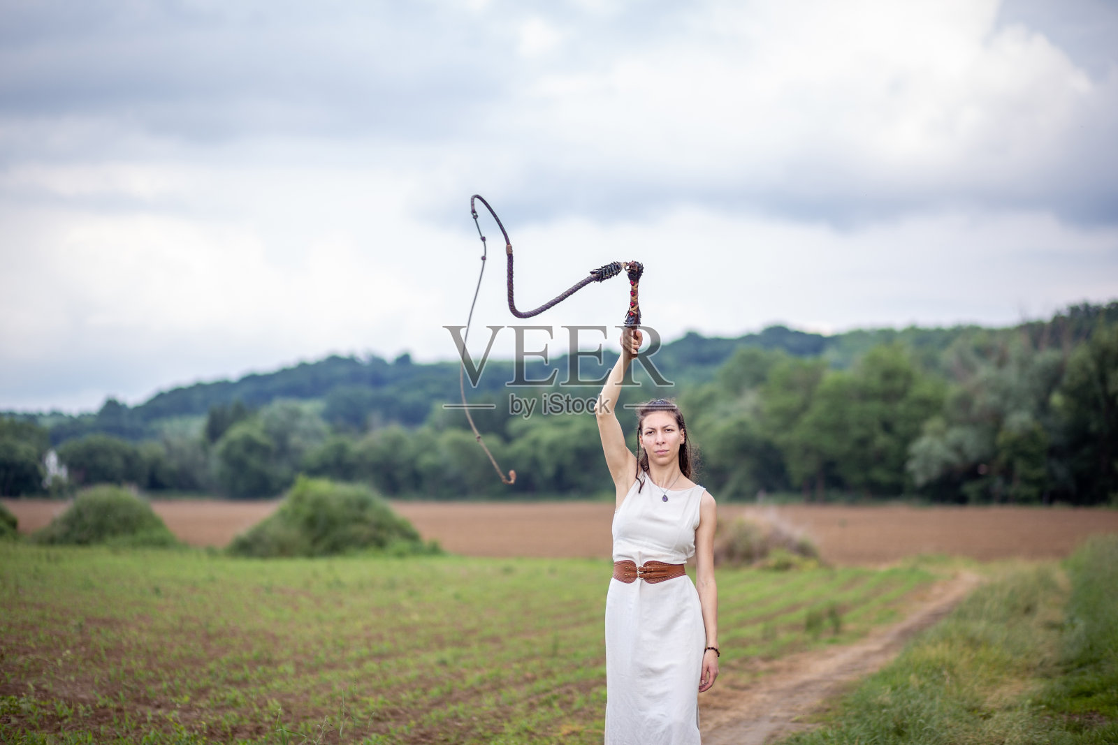 一个匈牙利女人站在草地上,穿着亚麻衣服,拿着鞭子照片摄影图片