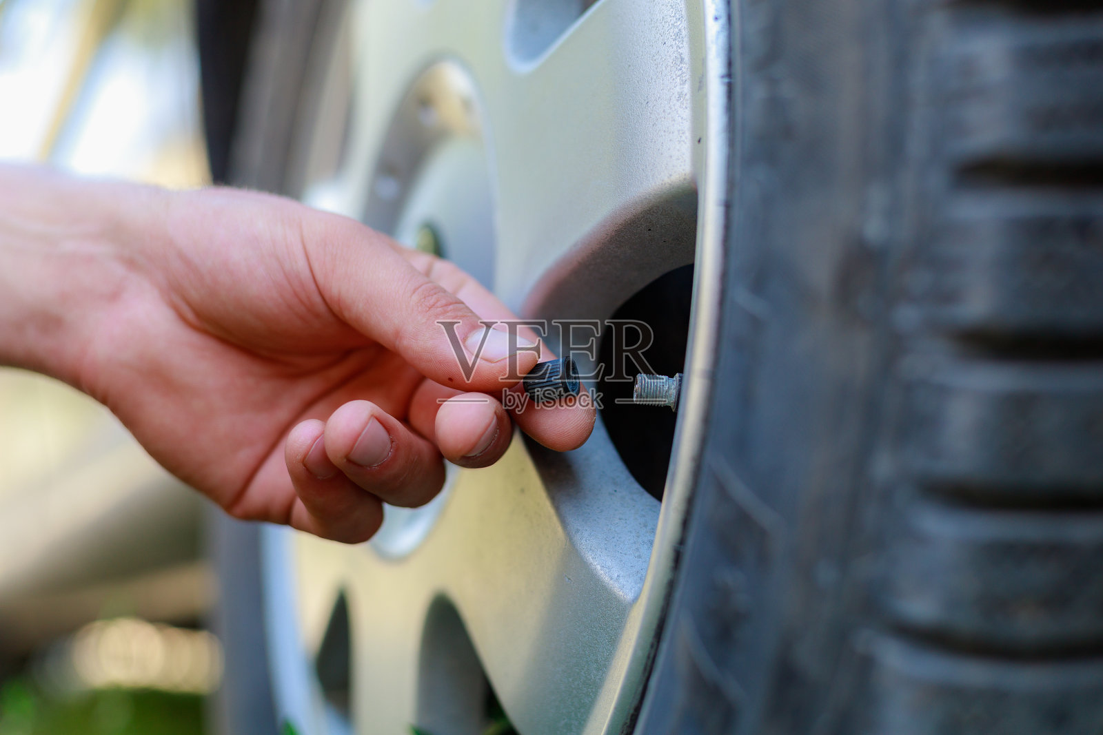 用手从车轮上拧开或旋开乳头帽。放置补气轮胎。关注帽子。照片摄影图片