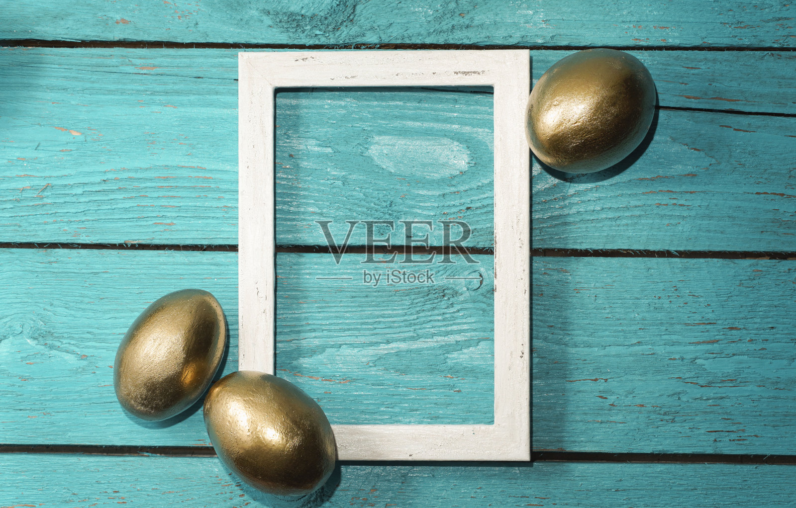 三个金色的复活节蛋与白色的复古框架在海蓝宝石质朴的古老的木制背景。时髦的复活节组成。复制文本空间。最小的复活节的概念。照片摄影图片