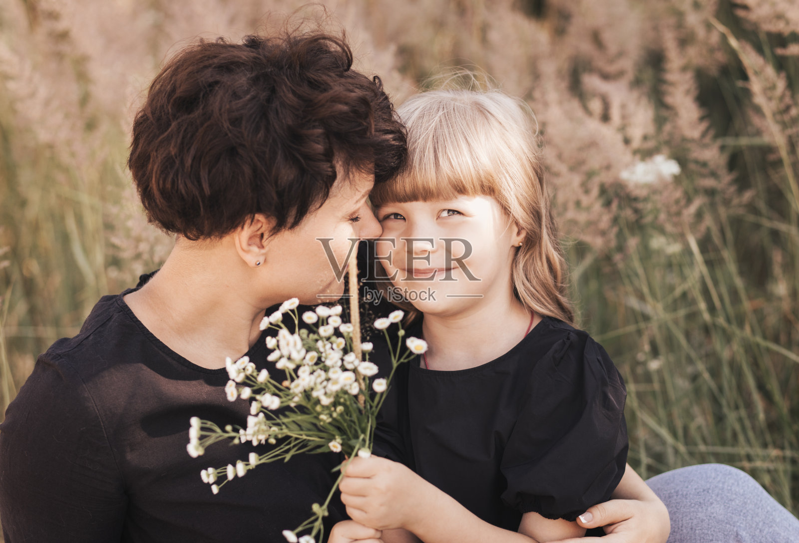 在夏天的大自然中,妈妈轻轻地拥抱着女儿,快乐的做母亲照片摄影图片