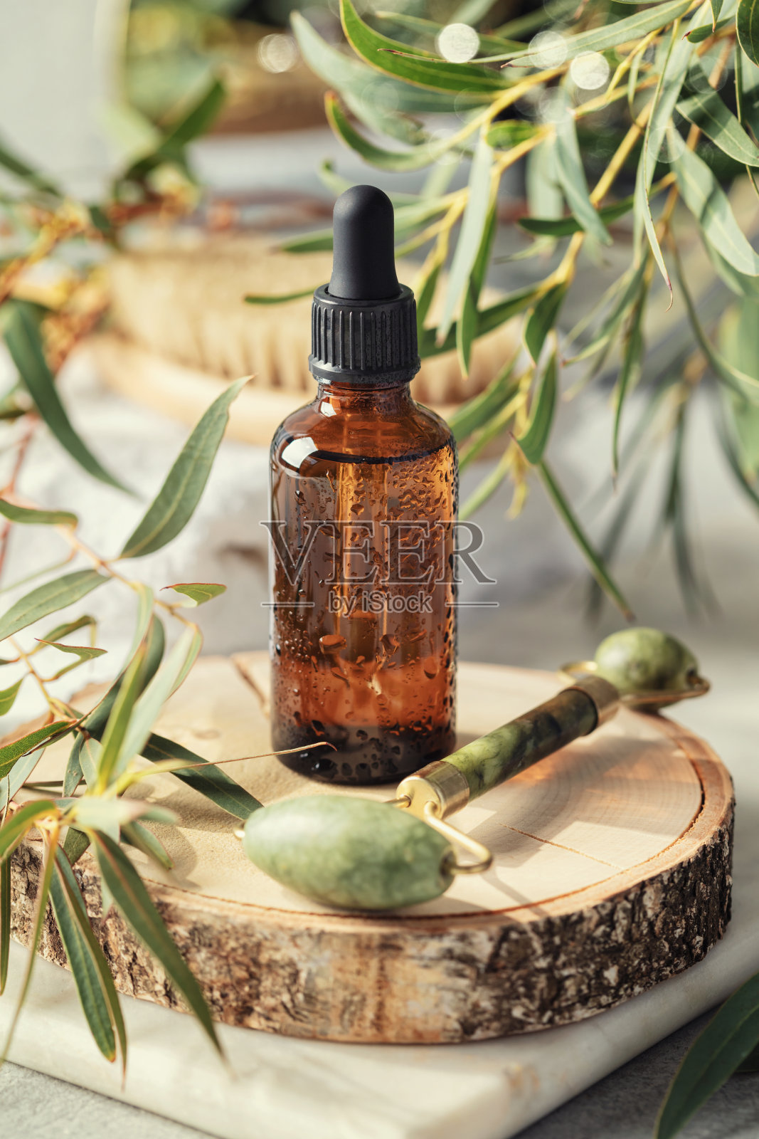 琥珀玻璃透明瓶木制几何基座基座与玉面辊和桉树叶照片摄影图片