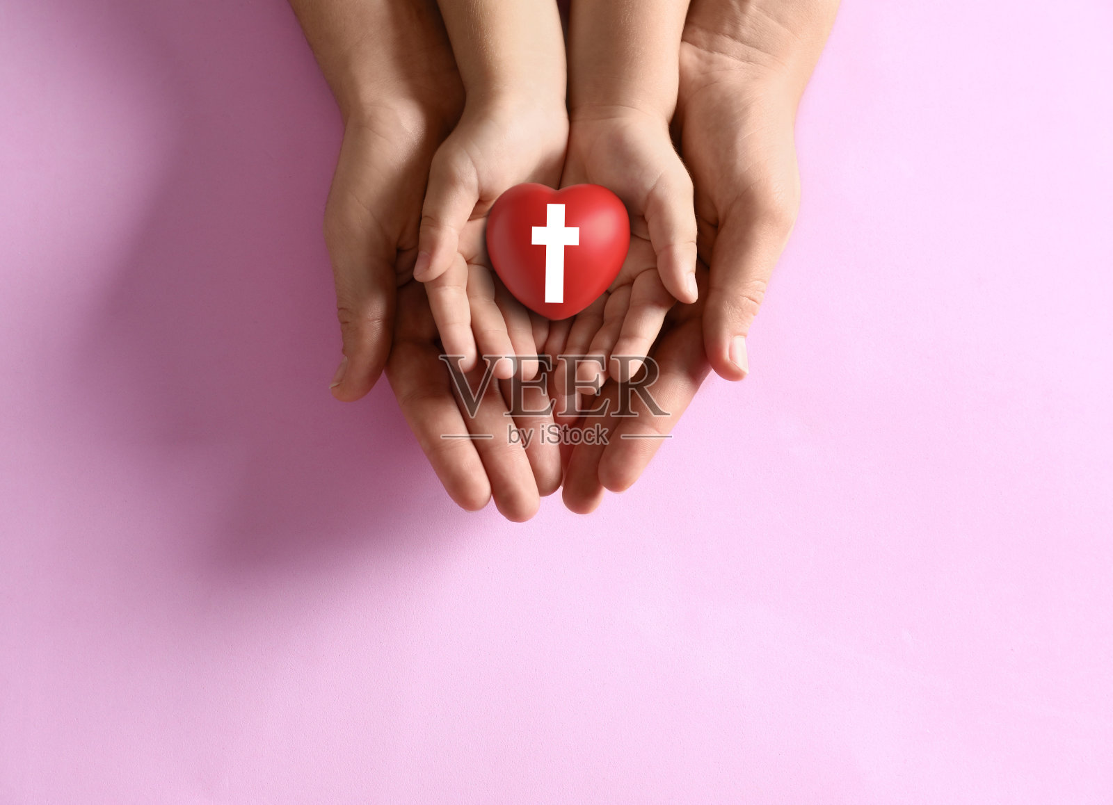 母亲和她的孩子抱着心形十字架符号在粉红色的背景,俯视图。基督教照片摄影图片