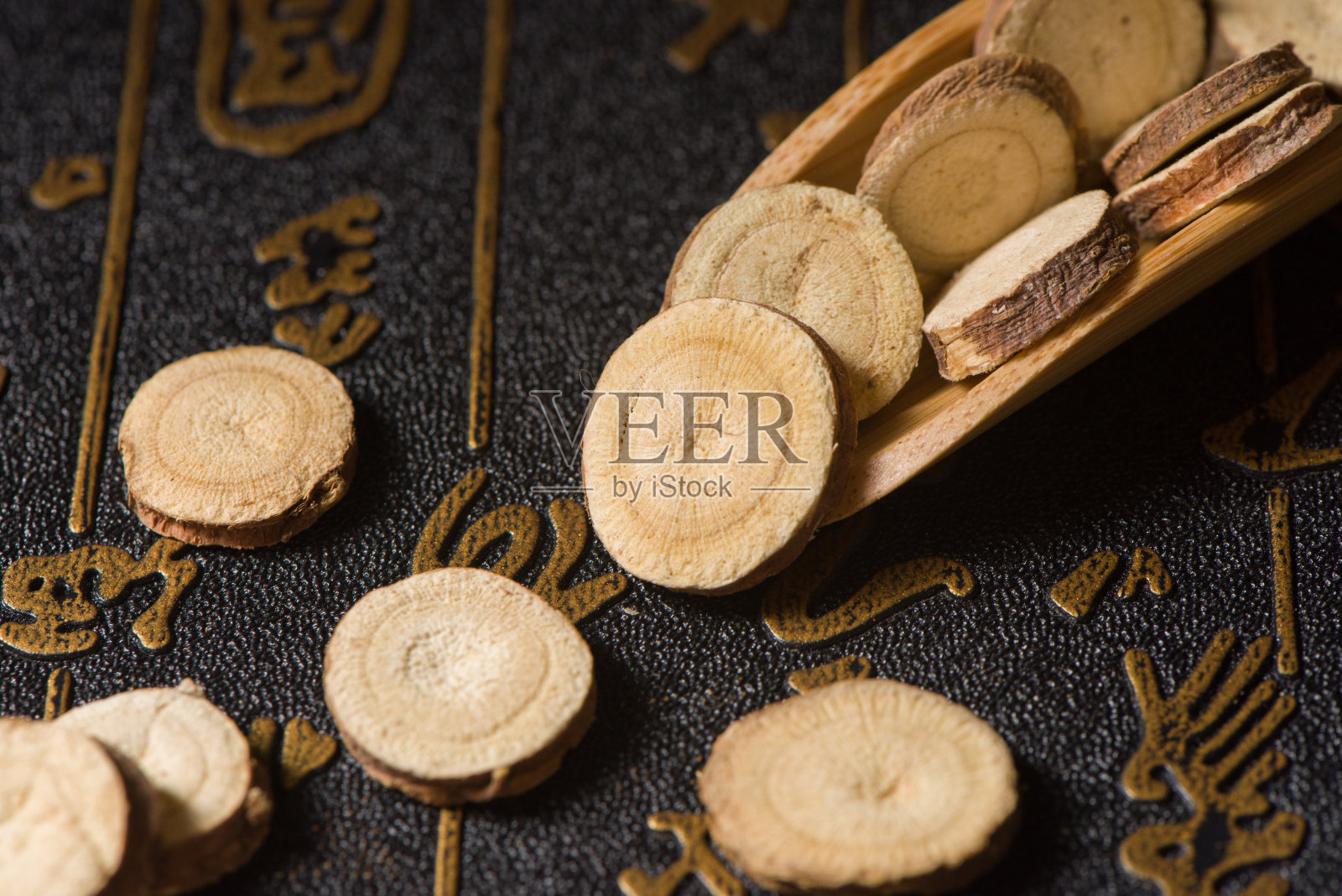 中草药,木制背景上的干甘草切片照片摄影图片