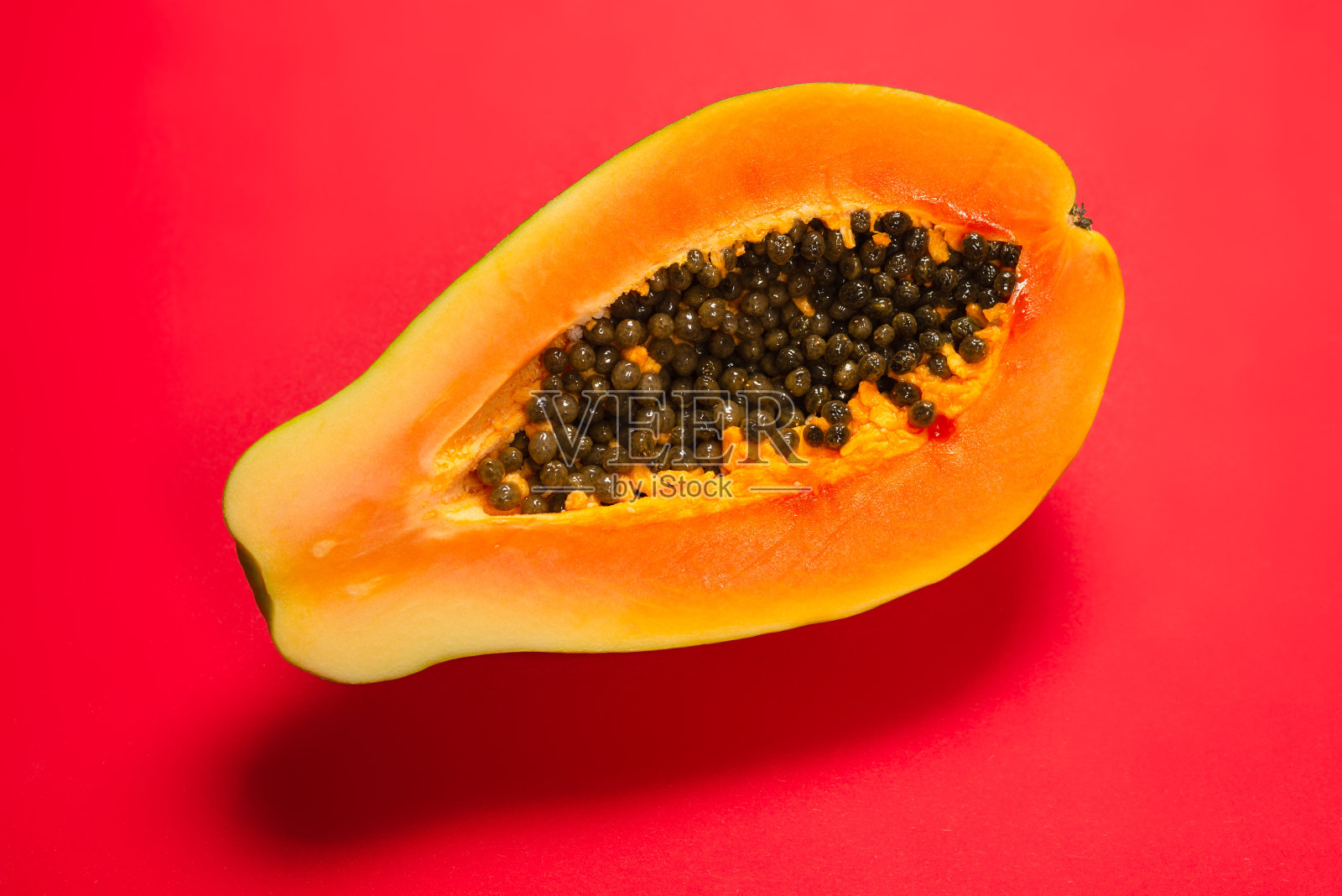 橙色背景上的木瓜。木瓜的一半。照片摄影图片