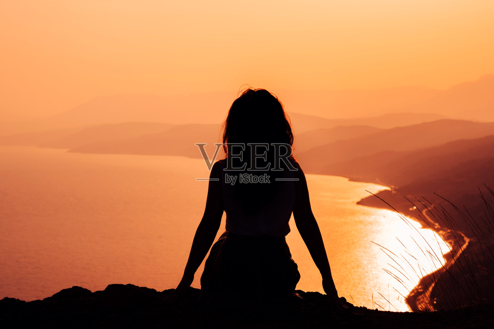 日落时俯瞰群山的悬崖上女人的剪影照片摄影图片