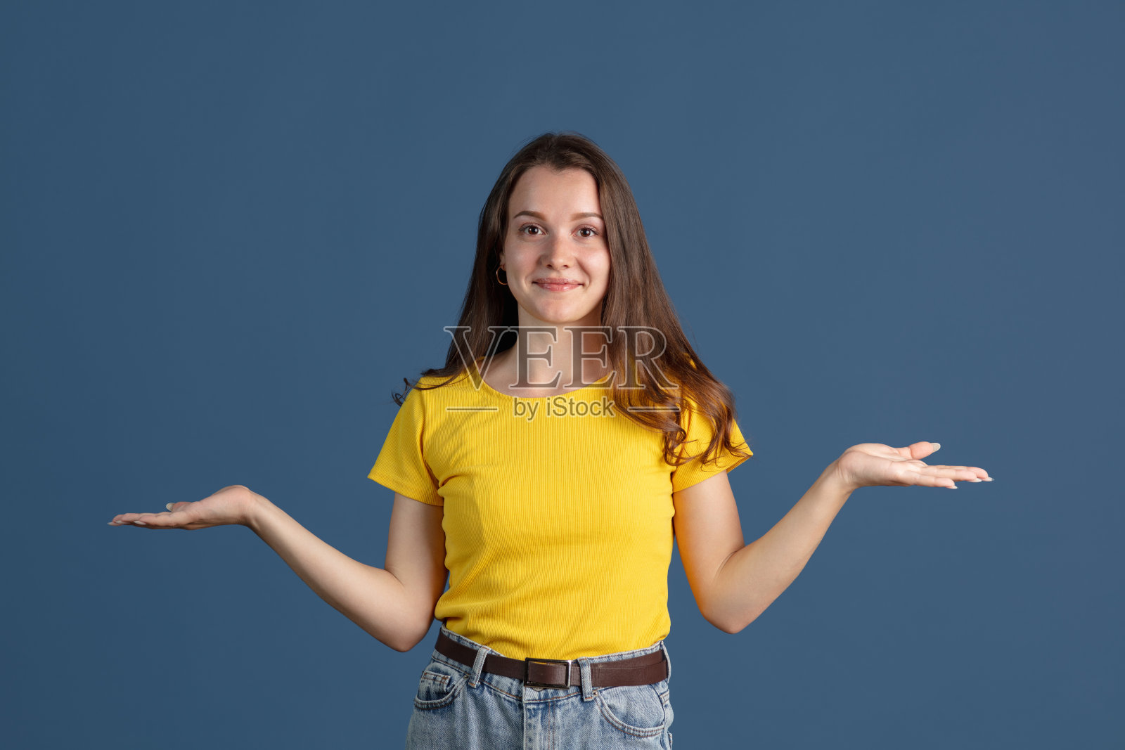 特写的年轻美丽的女孩穿着黄色衬衫孤立在蓝色的工作室背景照片摄影图片