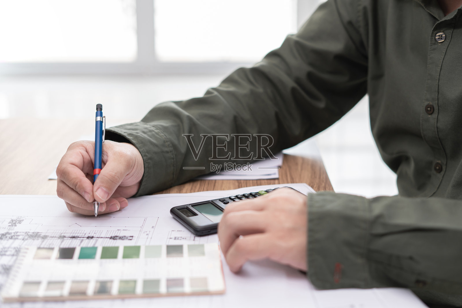 一个人用铅笔在工程工作中用计算器绘制图表和在桌子上绘图照片摄影图片