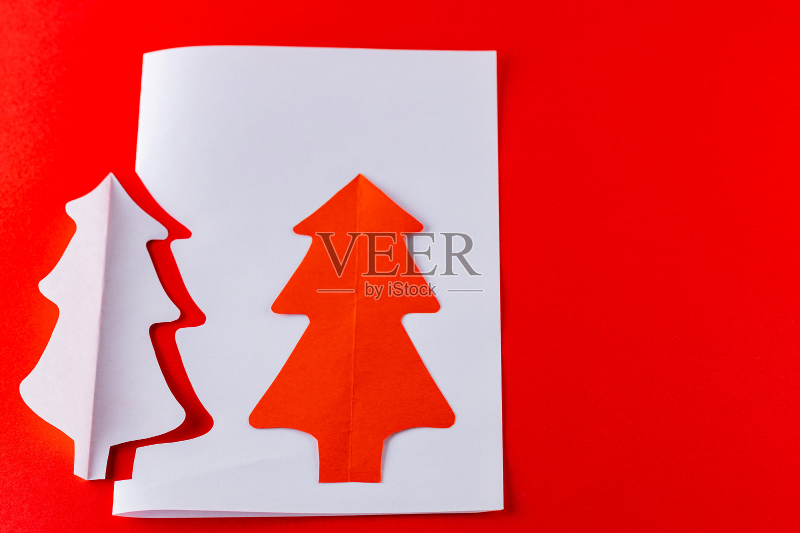 红色背景上的纸圣诞树。白纸圣诞树。圣诞节最小的概念照片摄影图片