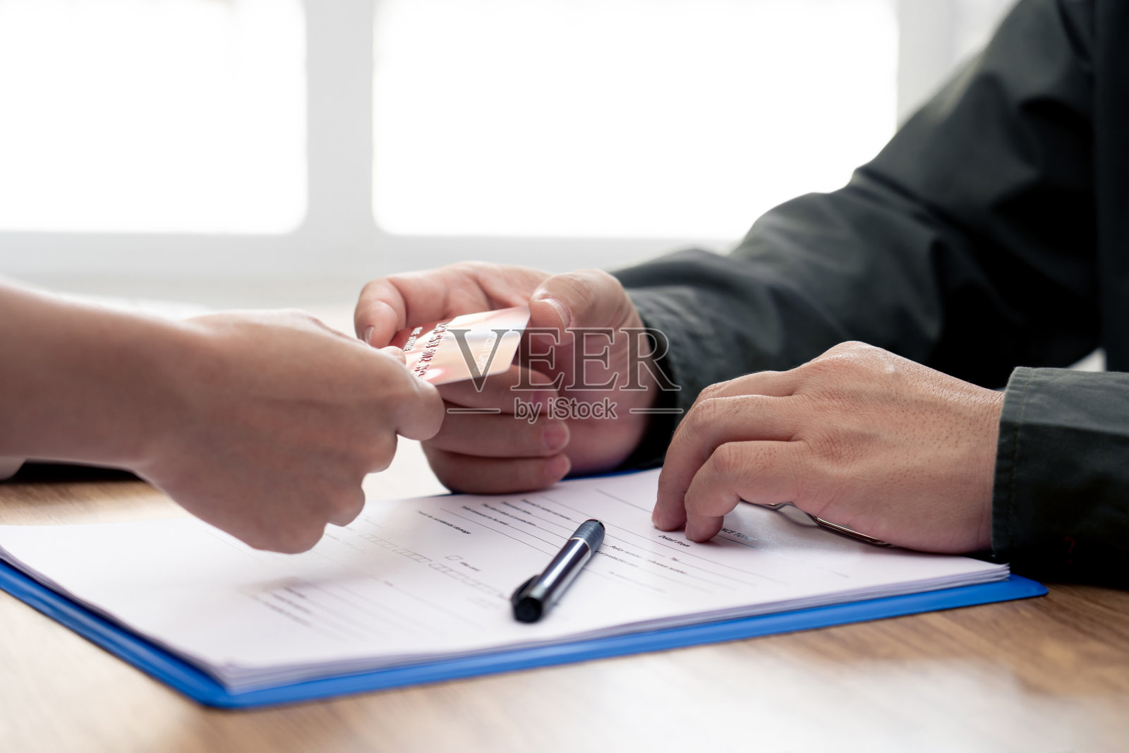 一名男子接受女性用信用卡支付汽车保险,并向官员介绍智能手机的细节:在办公室工作的概念照片摄影图片