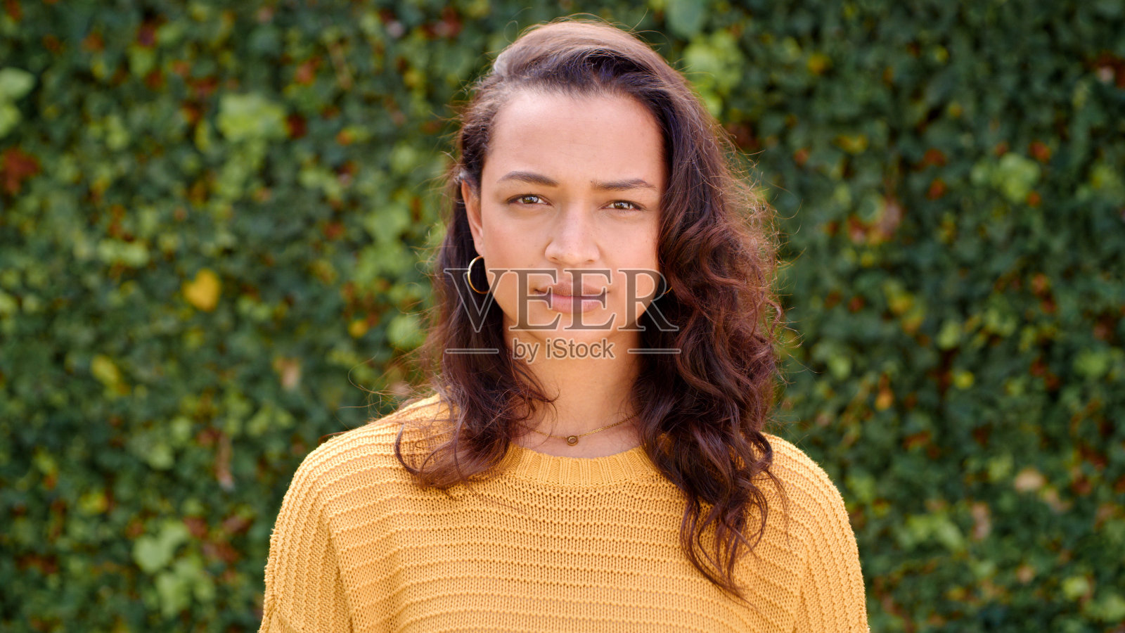 白天,一位美丽的年轻女子独自站在花园的篱笆旁照片摄影图片