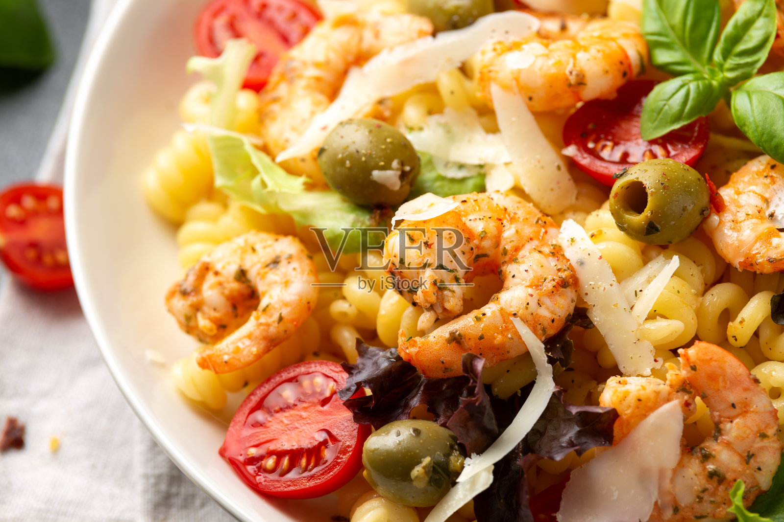 国王虾意面沙拉,佐以腌绿橄榄,圣女果和帕玛森芝士刨花。健康食品。照片摄影图片